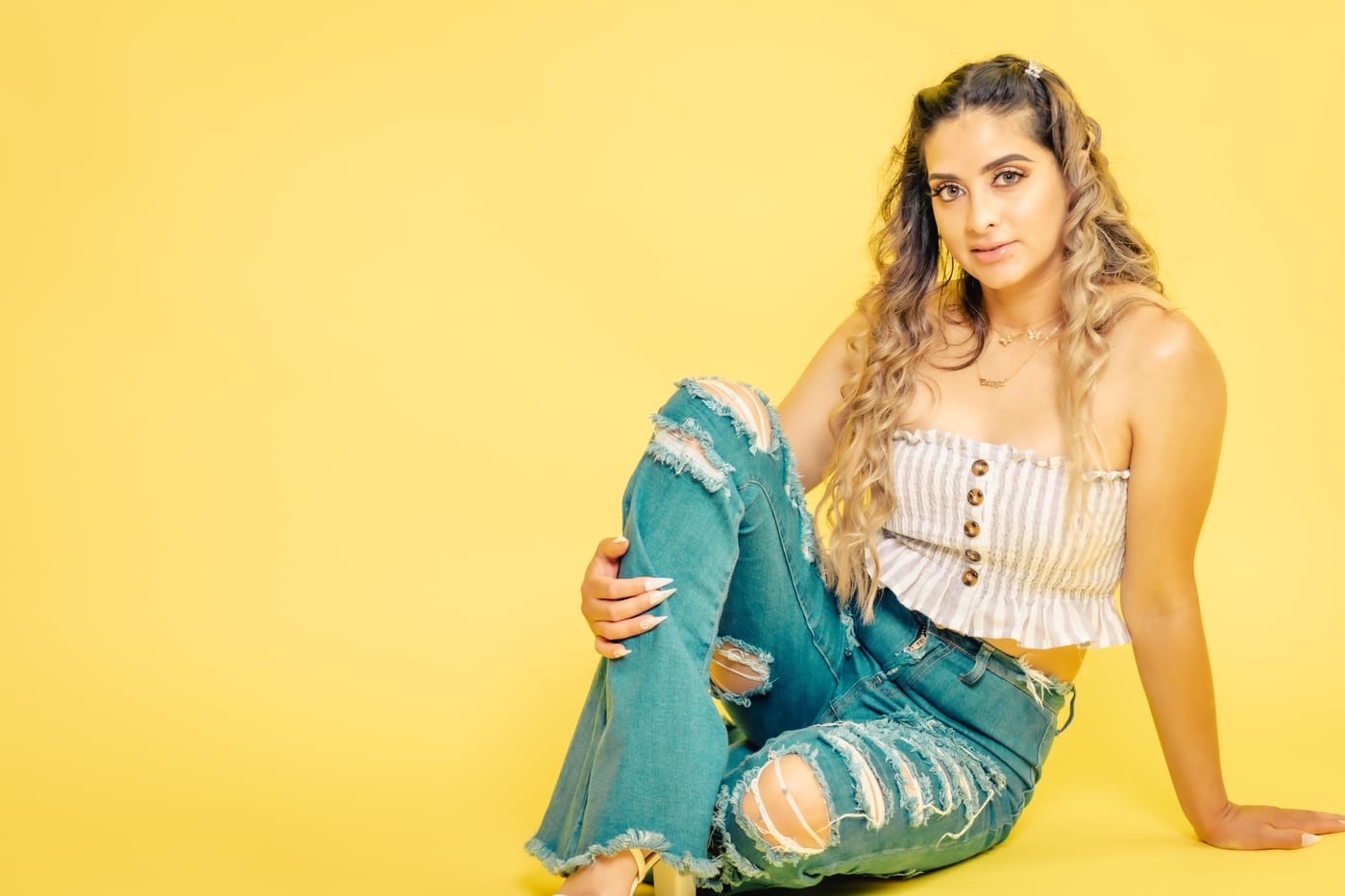 Woman ripped jeans, yellow bg, bright editorial.
