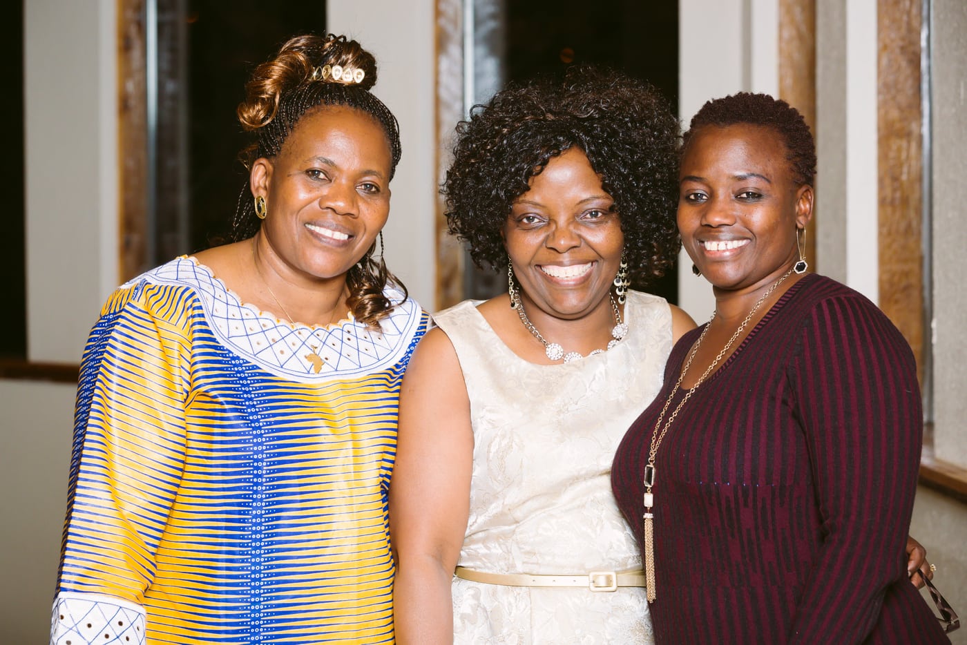 Three women in African attire, cultural event.