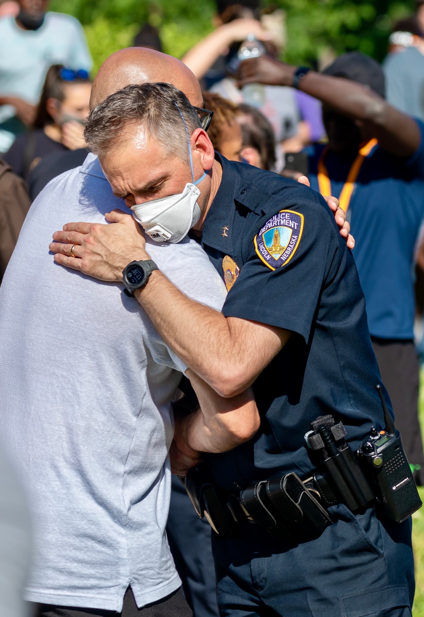 Officer embracing man, emotional, photojournalistic.