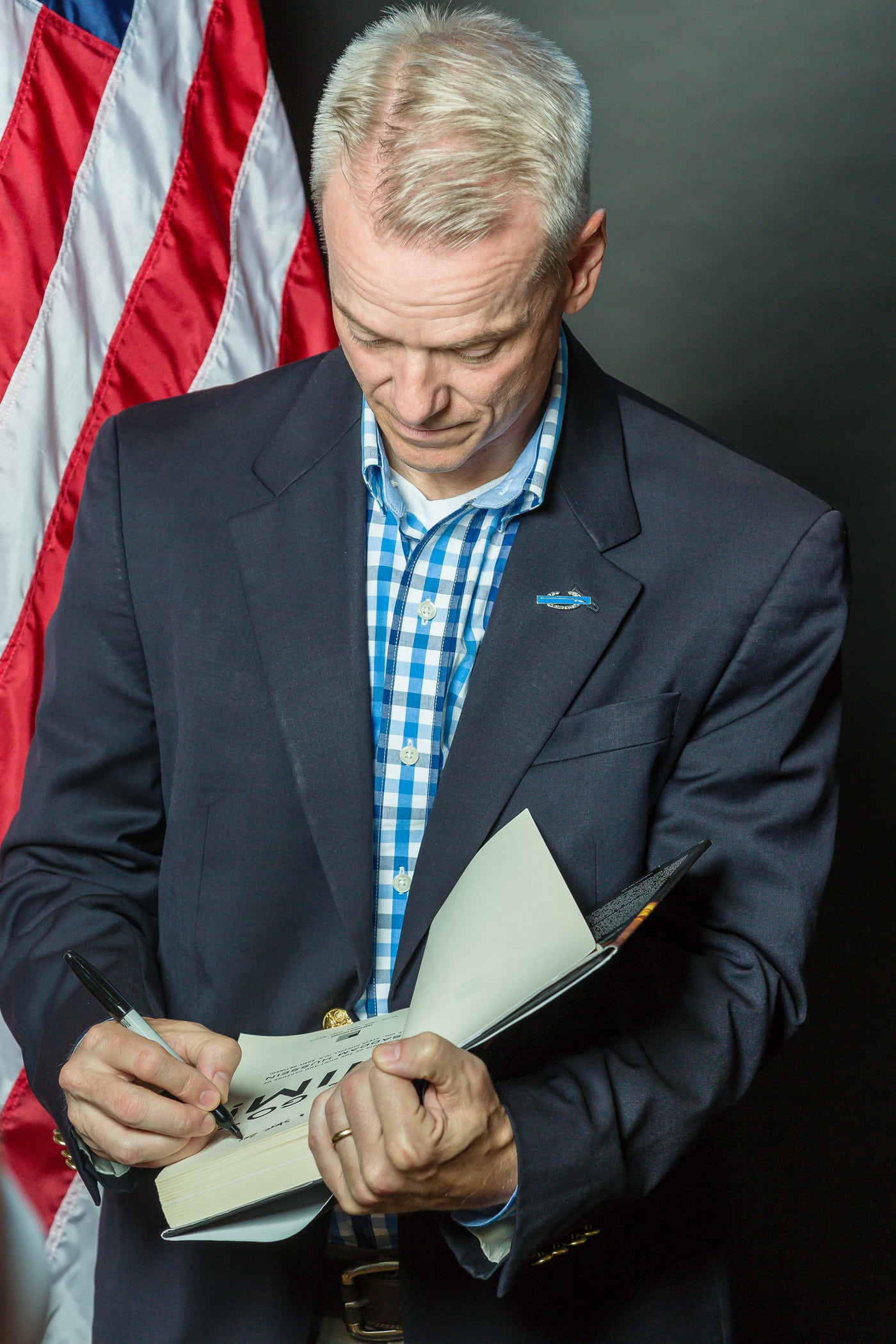 Man reading at podium, flag, professional.