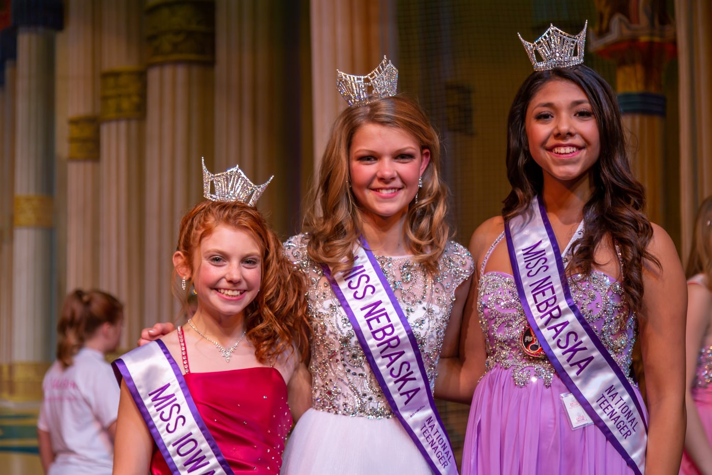Three honorees in pageant event setting.