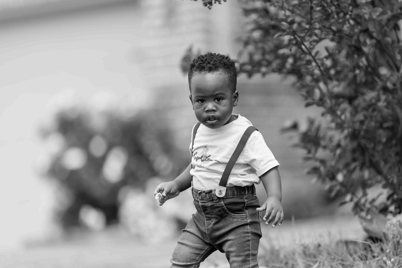 Black toddler suspenders in field, B&W, children.