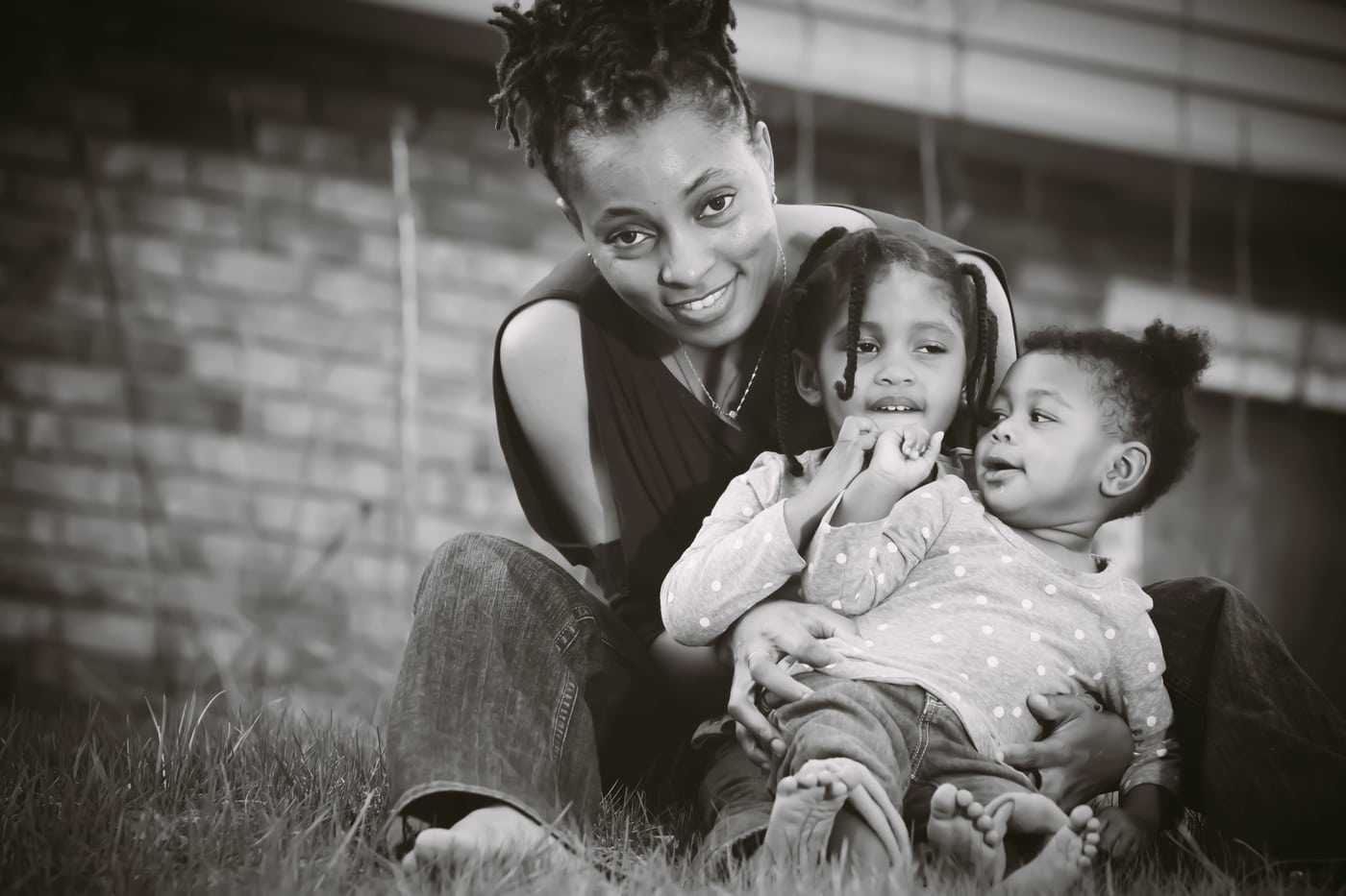 Mom + two kids, B&W, brick, family.