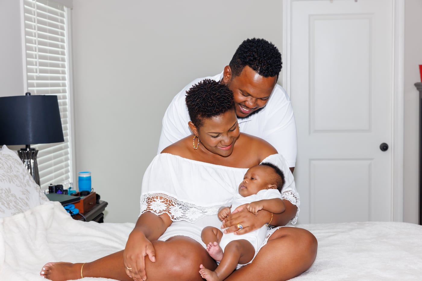 Parents cradling newborn on bed, tender in-home.