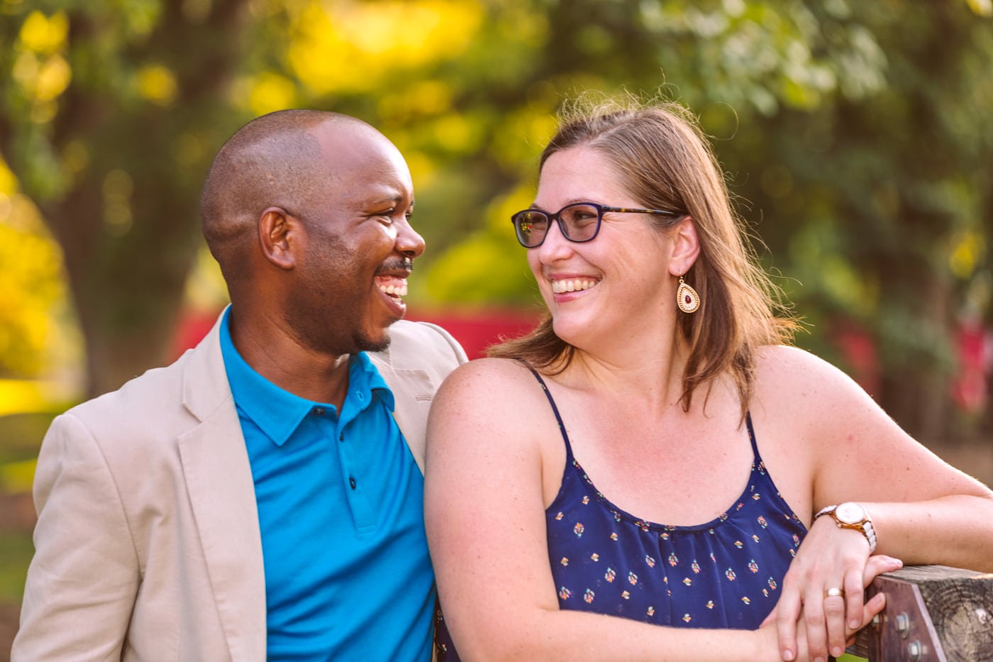 Couple by fence, laughing.