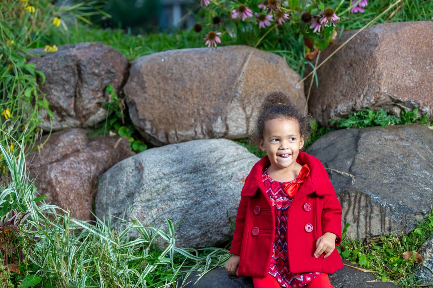 Child portrait in red coat with garden setting.