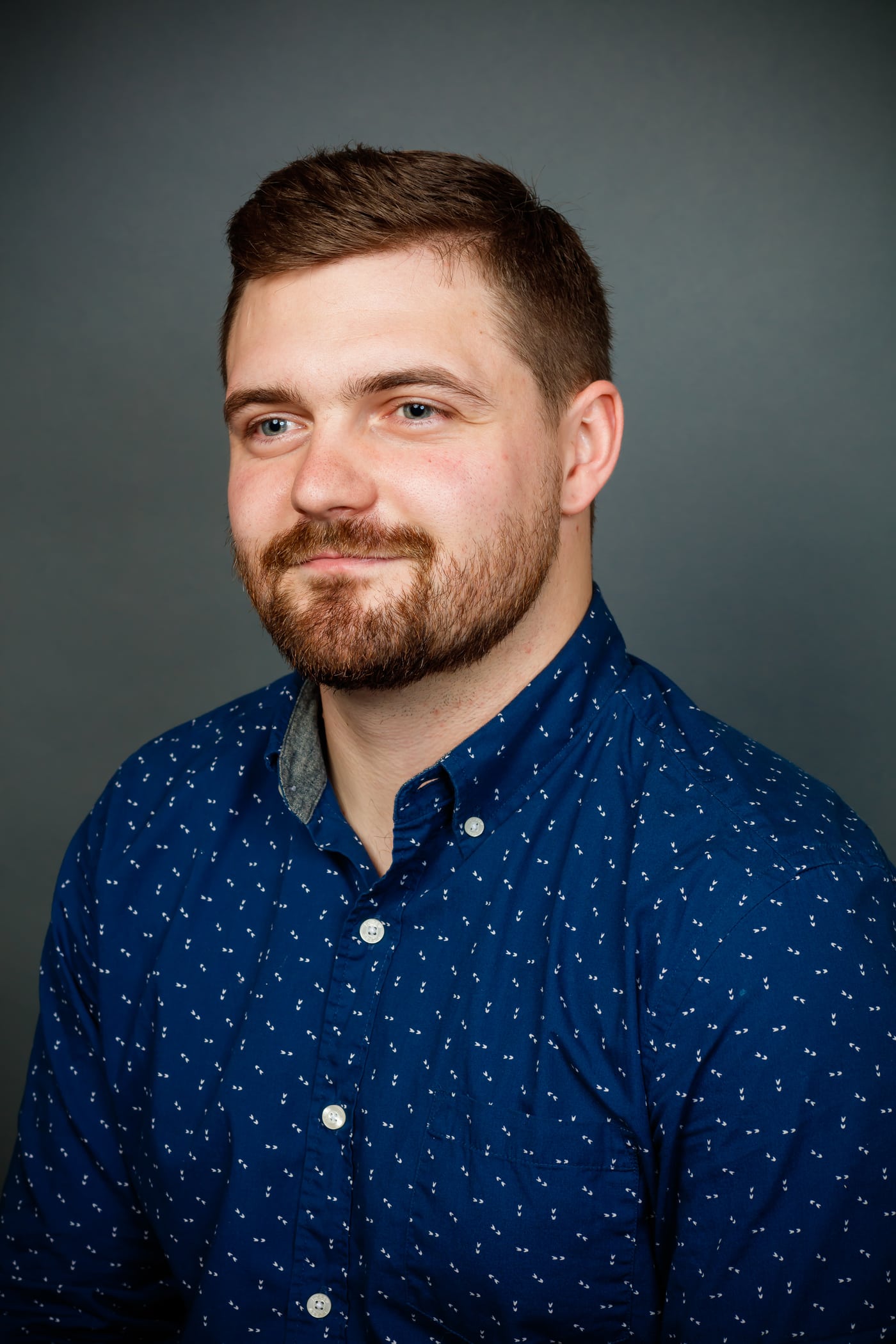 Man blue shirt, teal bg, clean headshot.