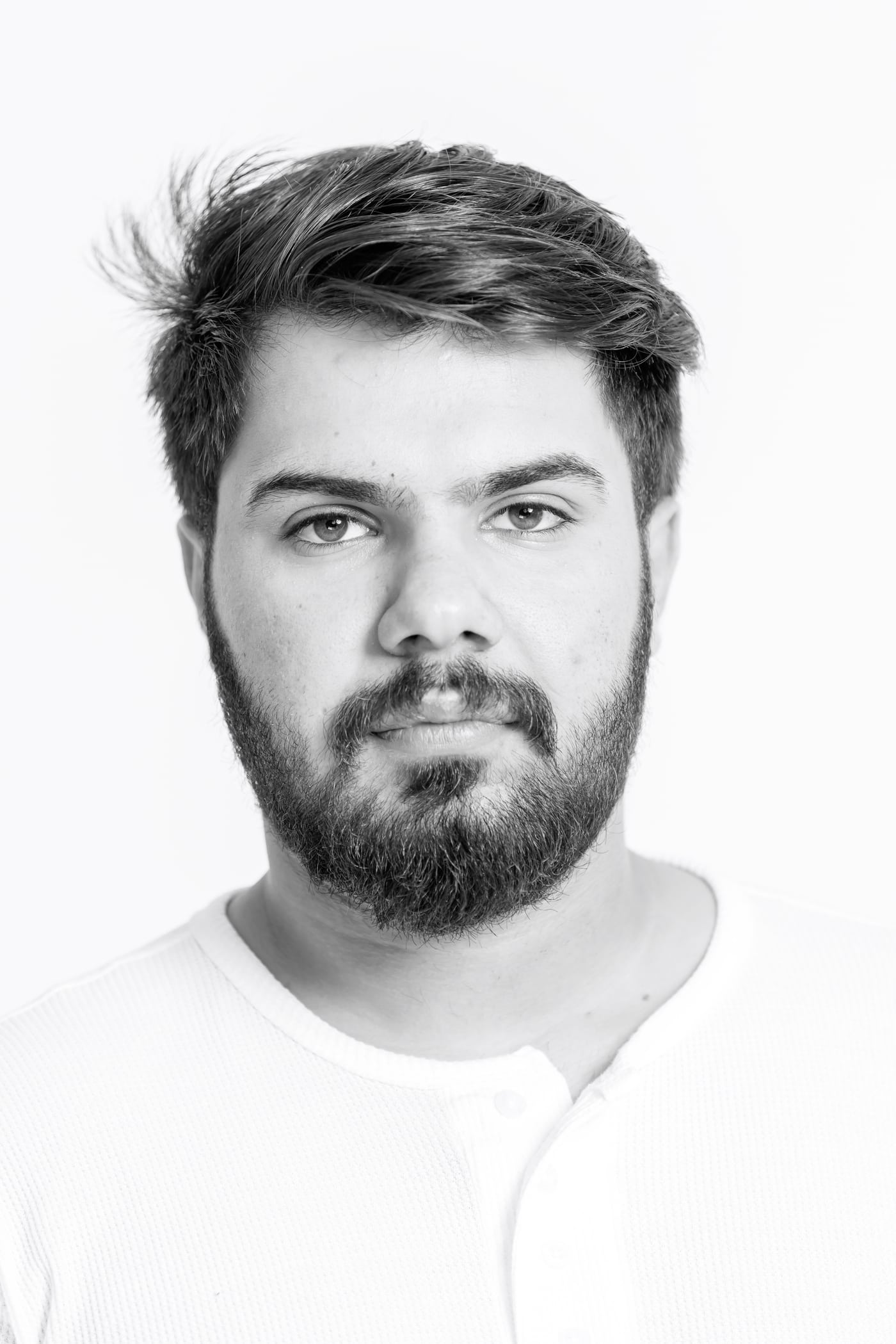 Male headshot B&W, white bg, editorial.