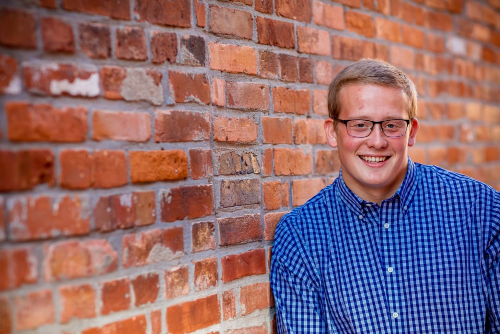 Executive male brick-background headshot, approachable and polished.