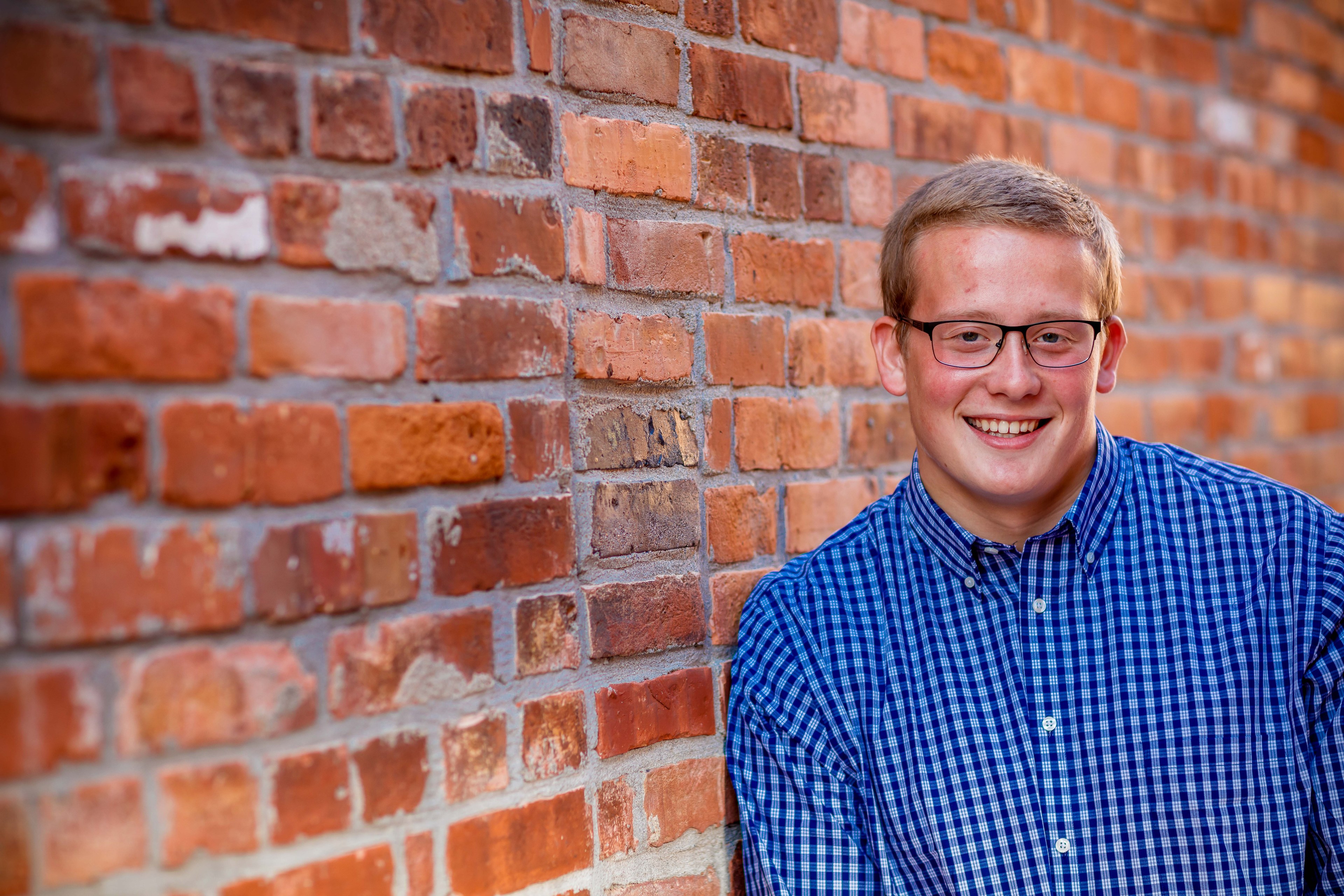 Executive male brick-background headshot, approachable and polished.