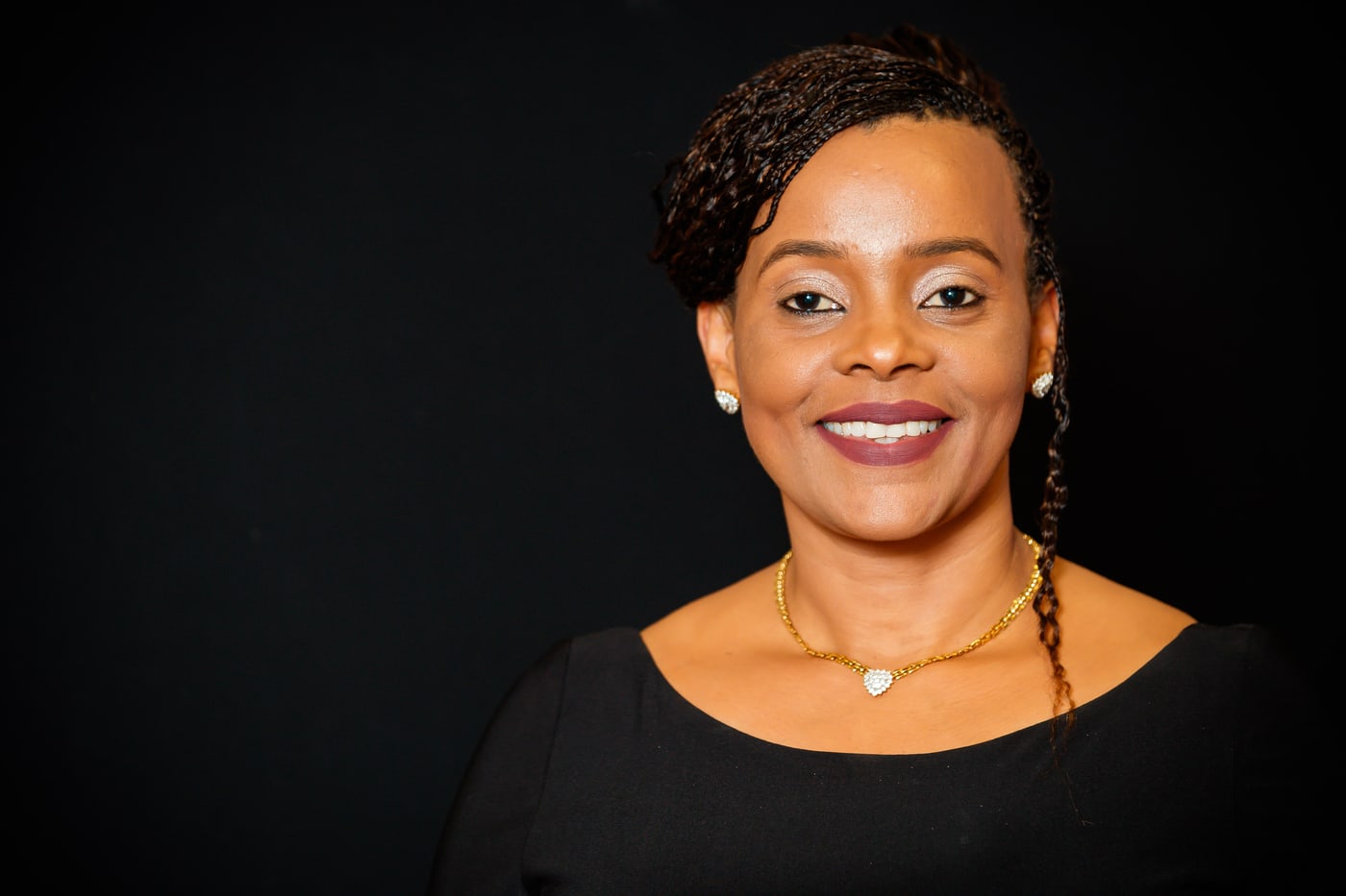 Executive woman, black top, dark bg, polished headshot.
