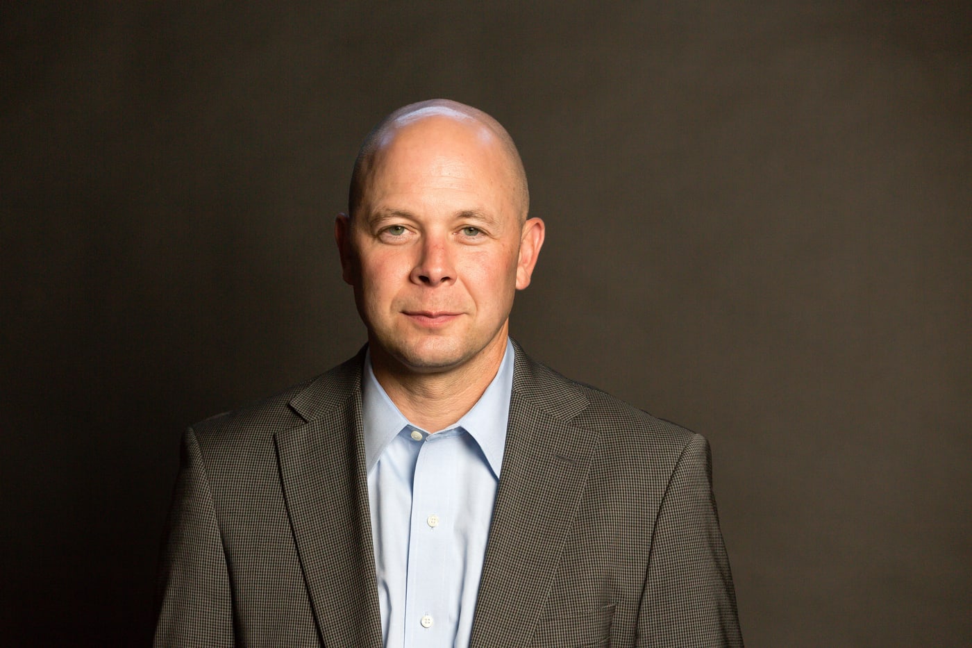 Executive man gray suit, dark bg, strong headshot.