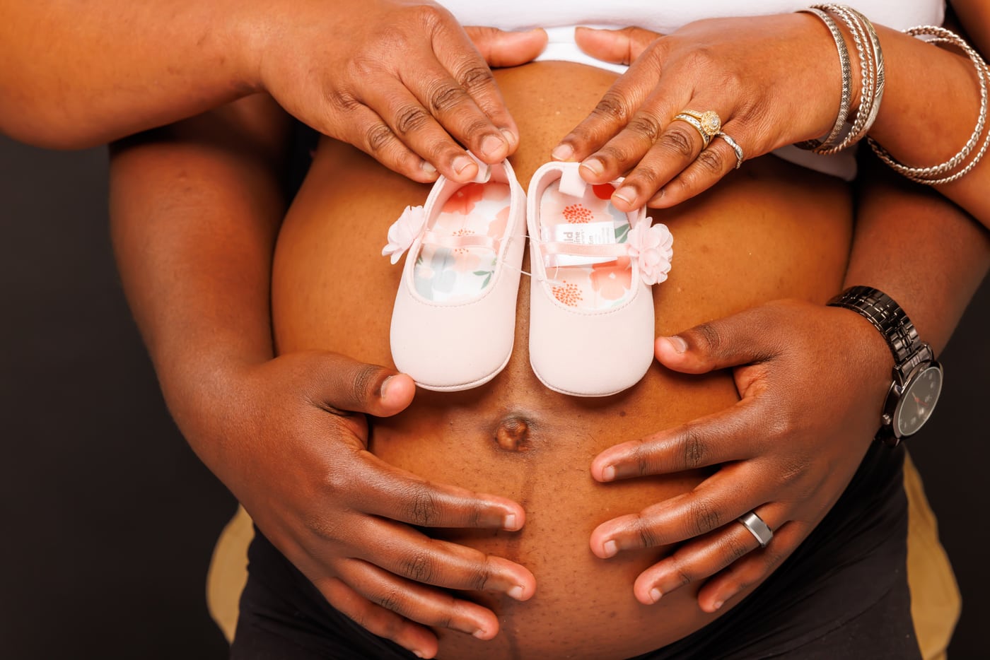 Belly with baby booties, hands, maternity detail.