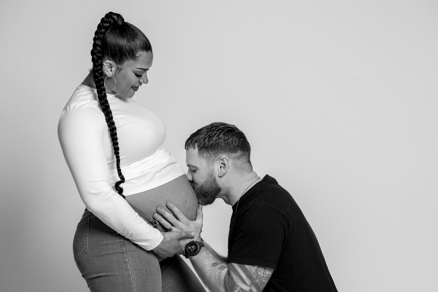 Maternity couple B&W, kissing belly.