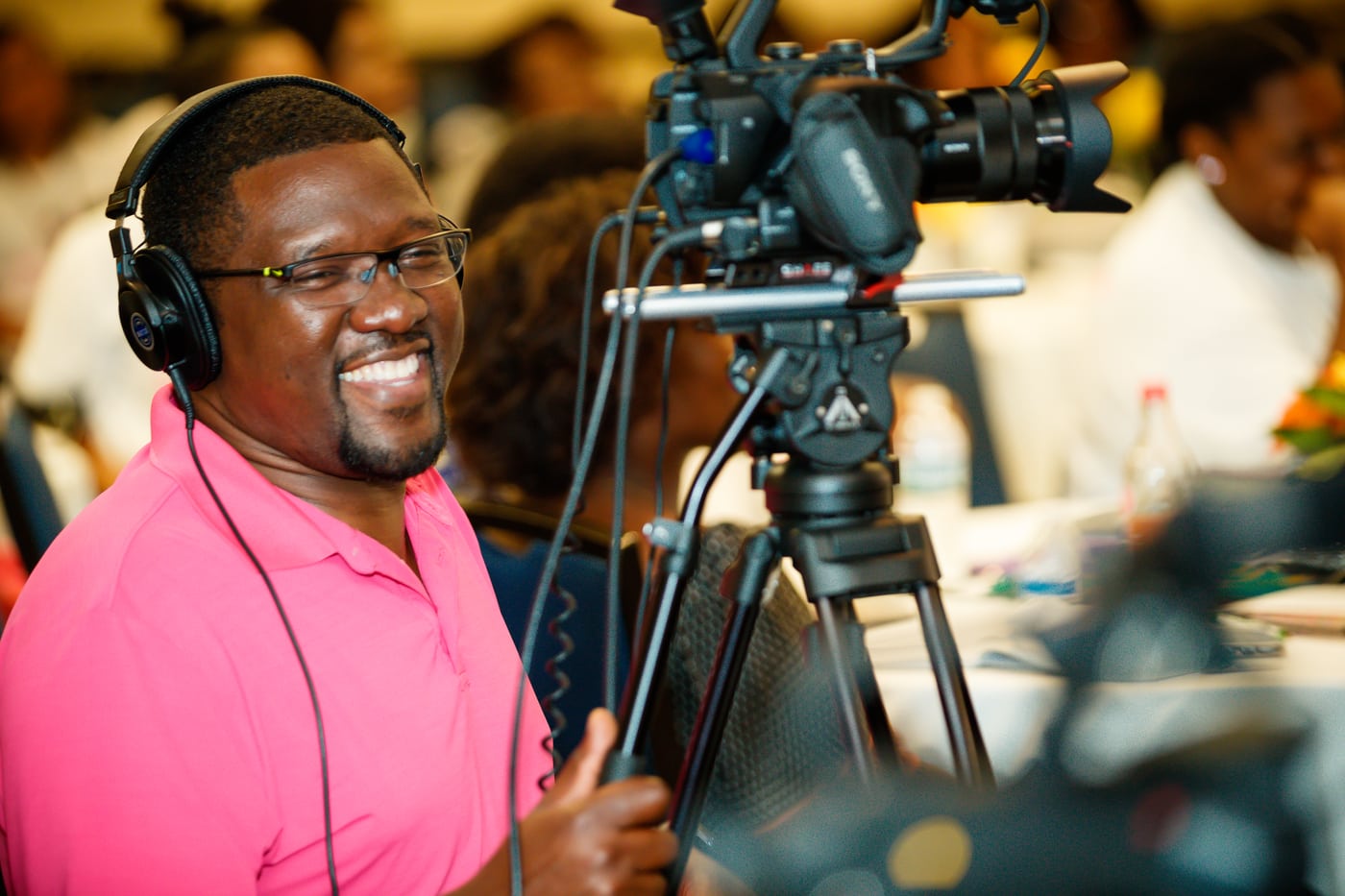 Videographer with cine camera + headphones, studio motion/behind-the-scenes.