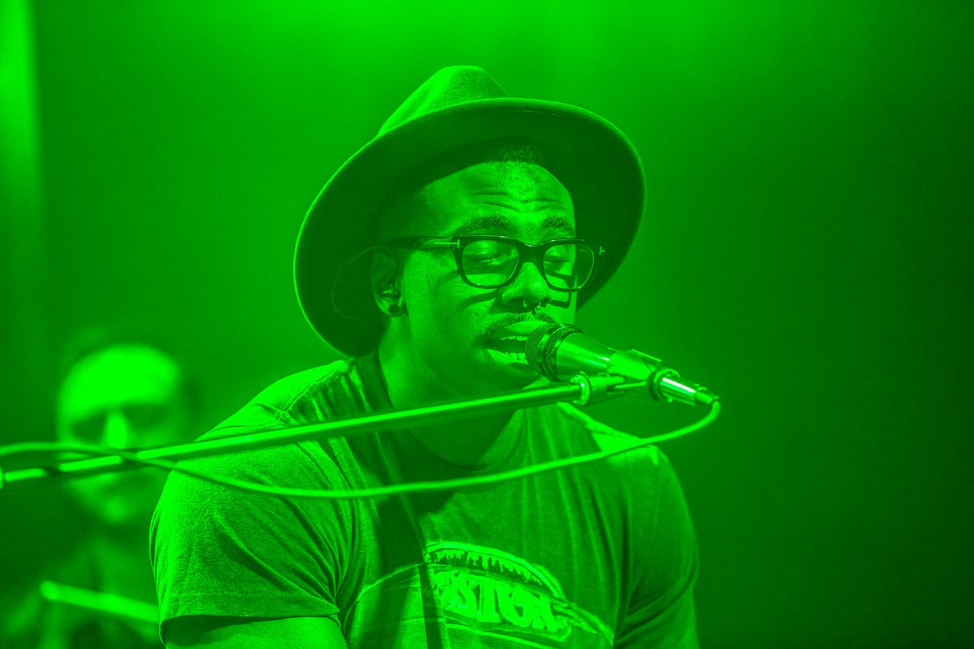 Singer under green stage light, live performance.