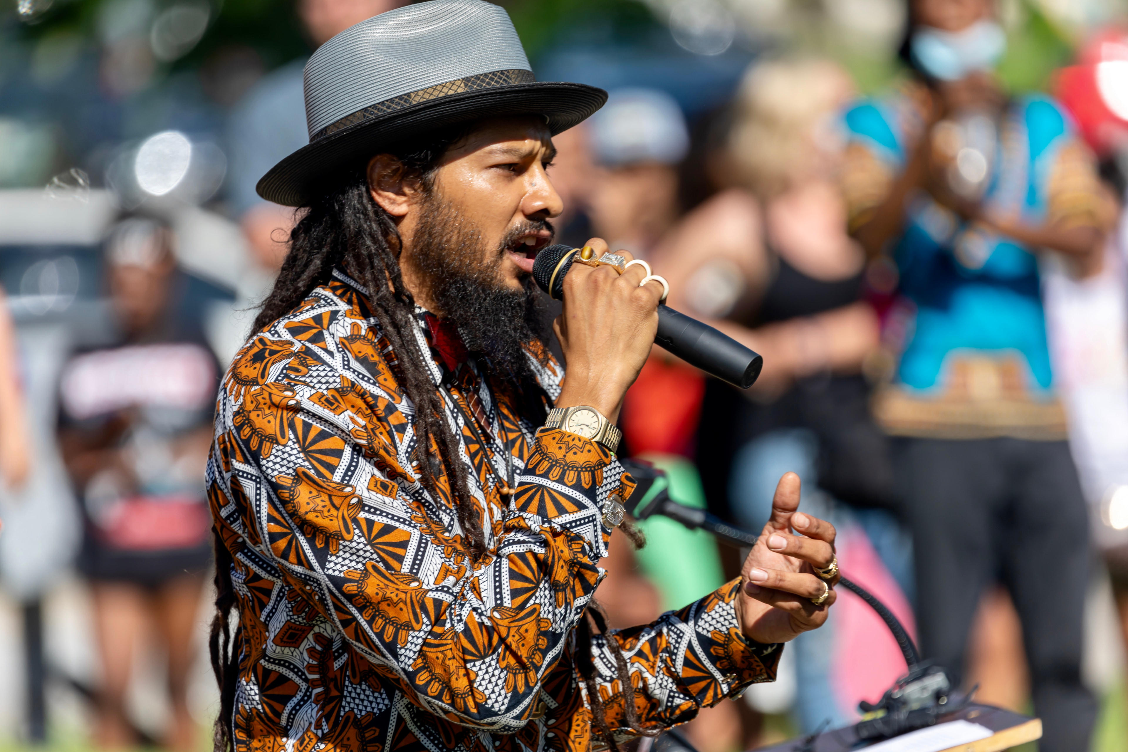 Man singing, African print, crowd, live performance.
