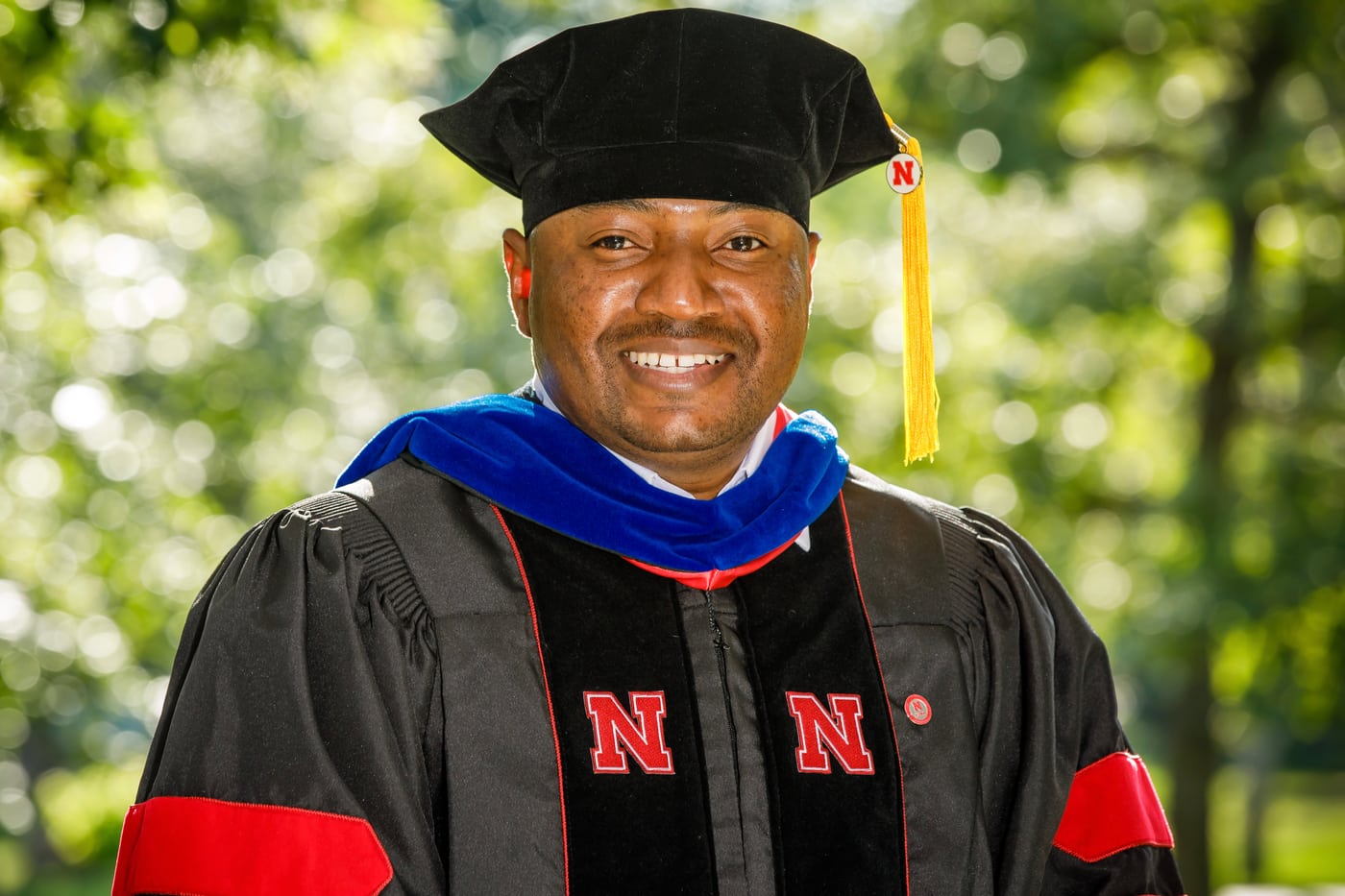 Man in doctoral regalia, Nebraska, dignified executive portrait.