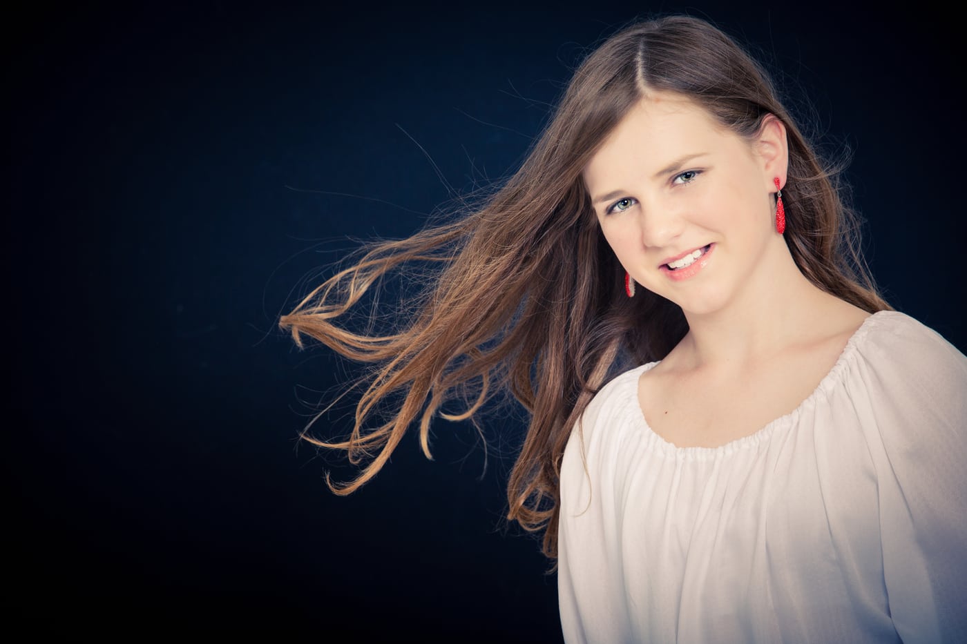 Woman white top, windblown hair, warm smile, lovely.