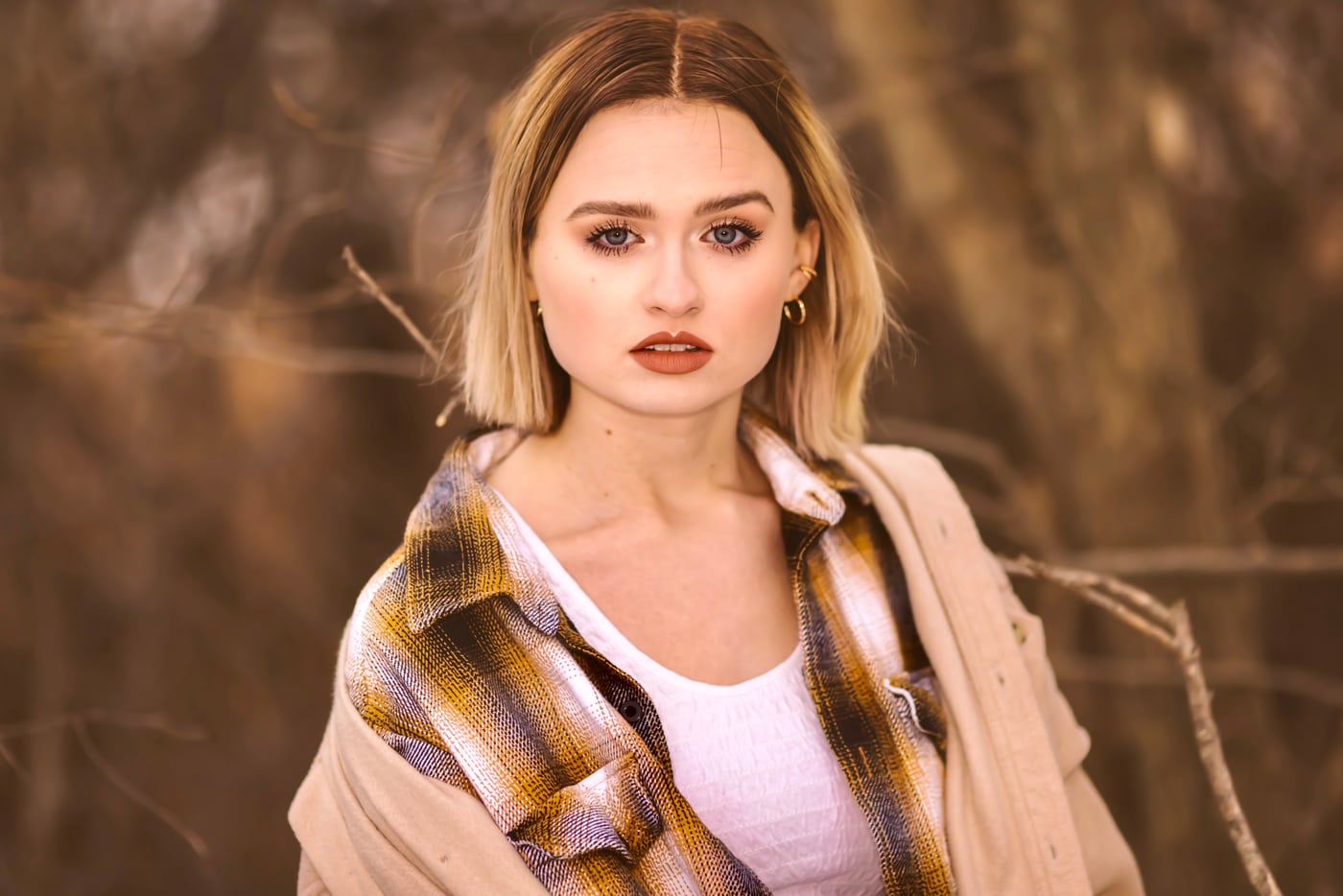 Woman plaid + tan jacket, golden bokeh, editorial.