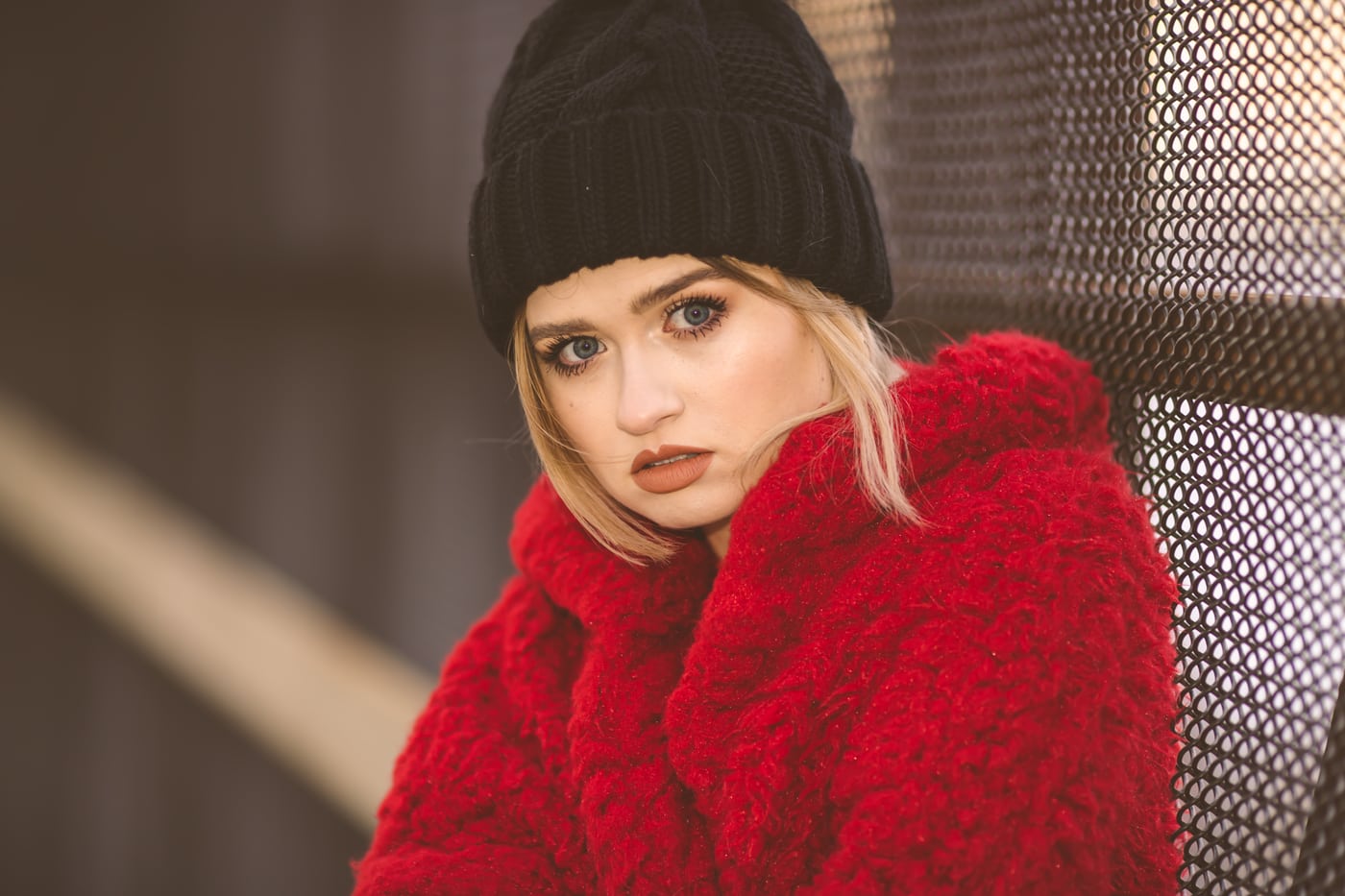 Woman red fur coat + beanie, dramatic, fashion editorial.