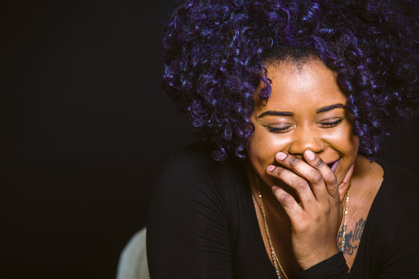 Woman purple hair, laughing, dark, genuine joy.
