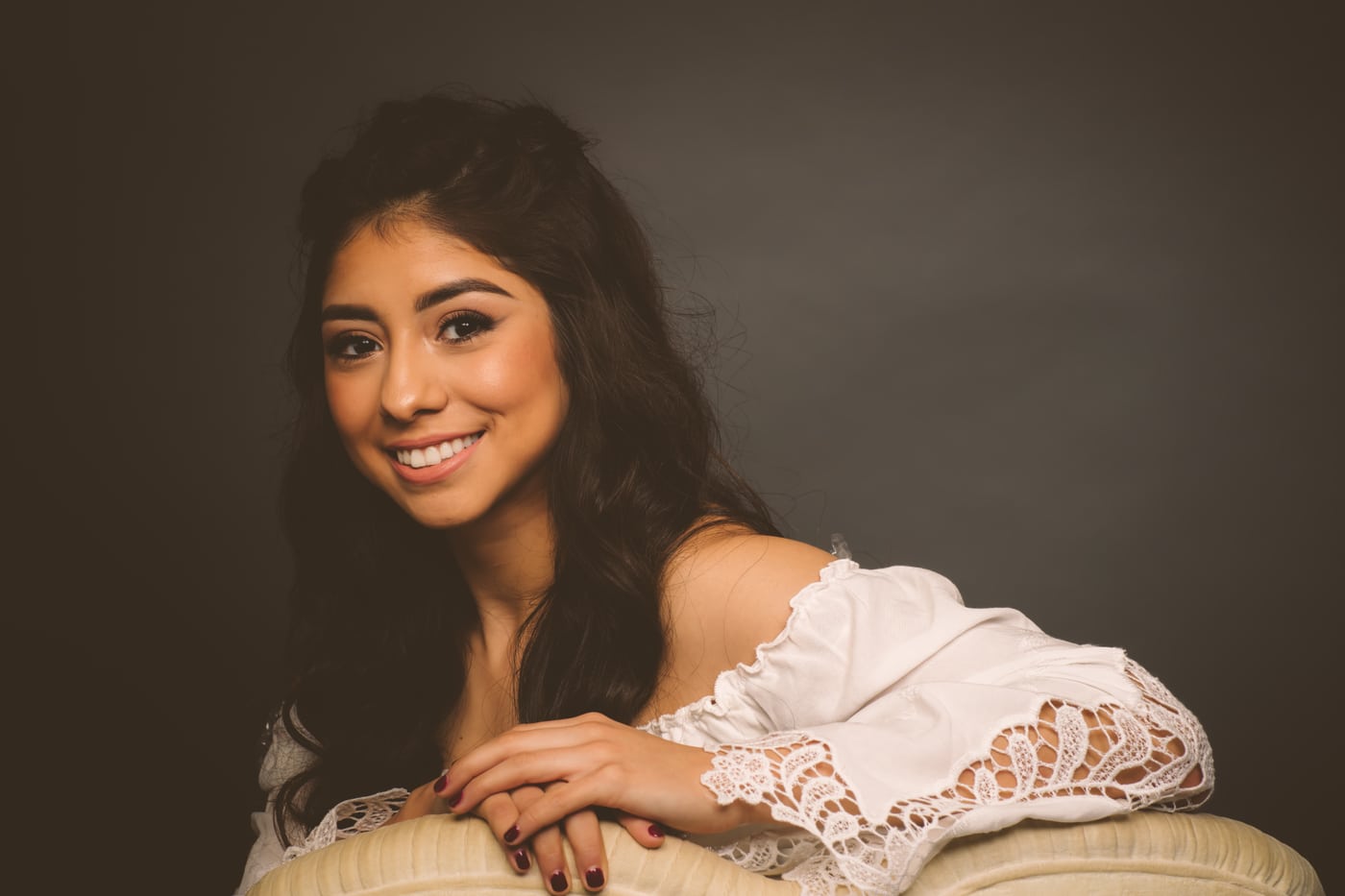 White off-shoulder, warm smile, moody studio.