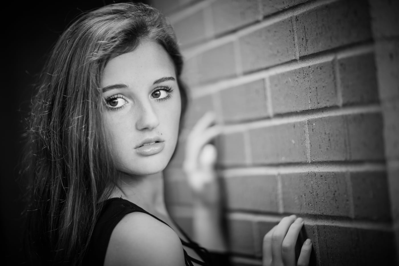 Senior girl at brick wall, B&W moody.