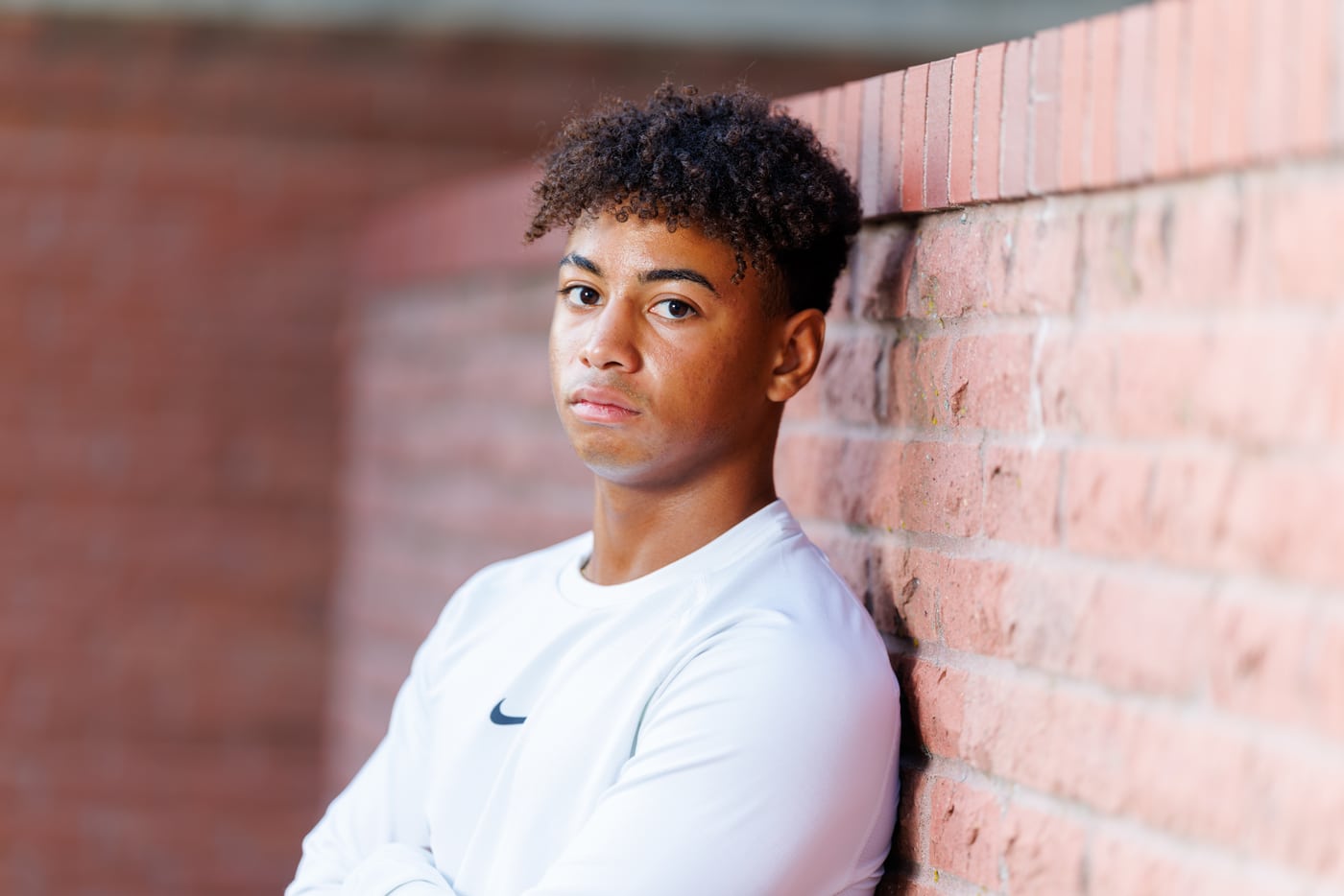 Young man white Nike, brick wall, strong.