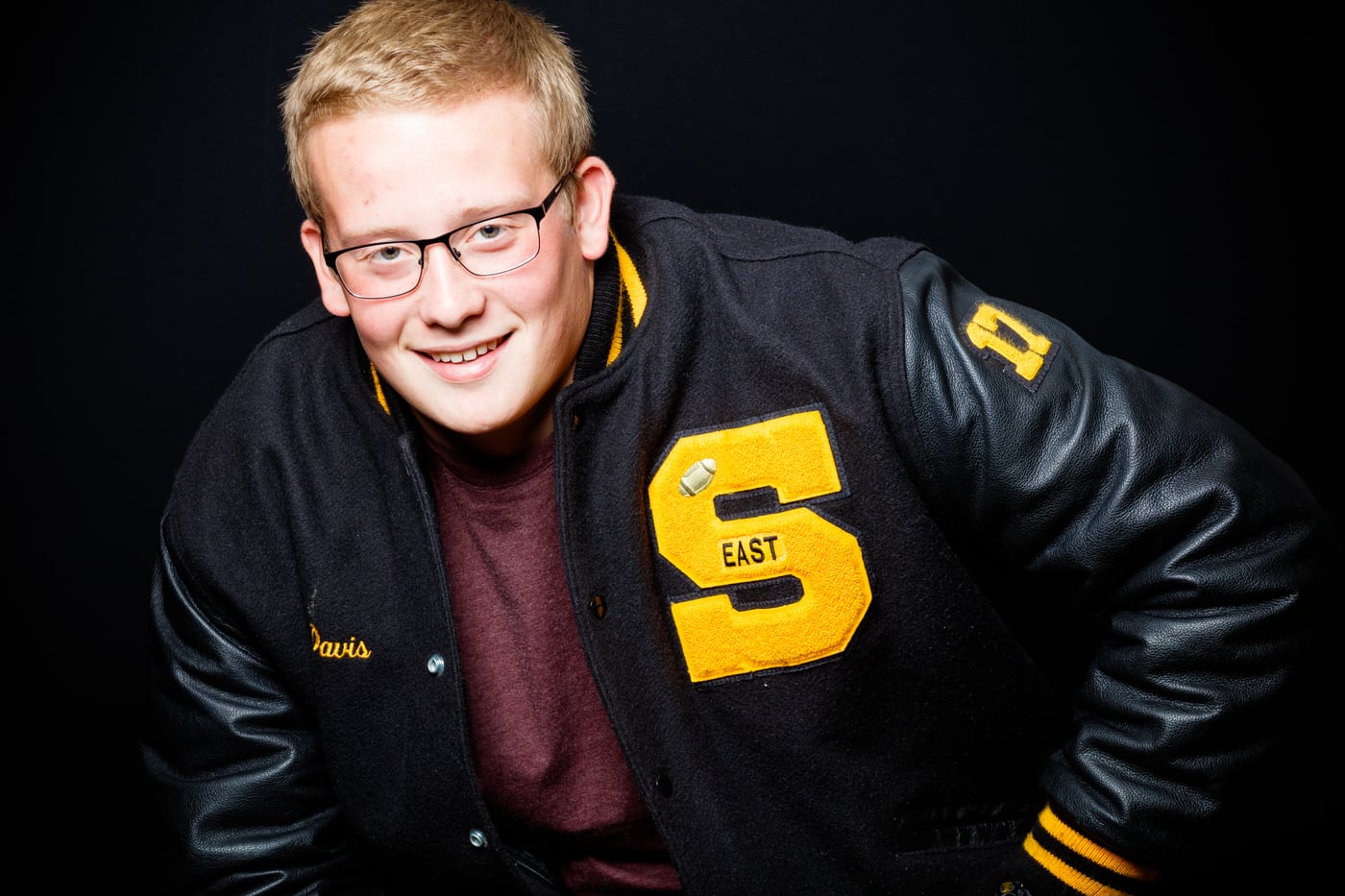 Senior guy East letterman jacket, dark bg.