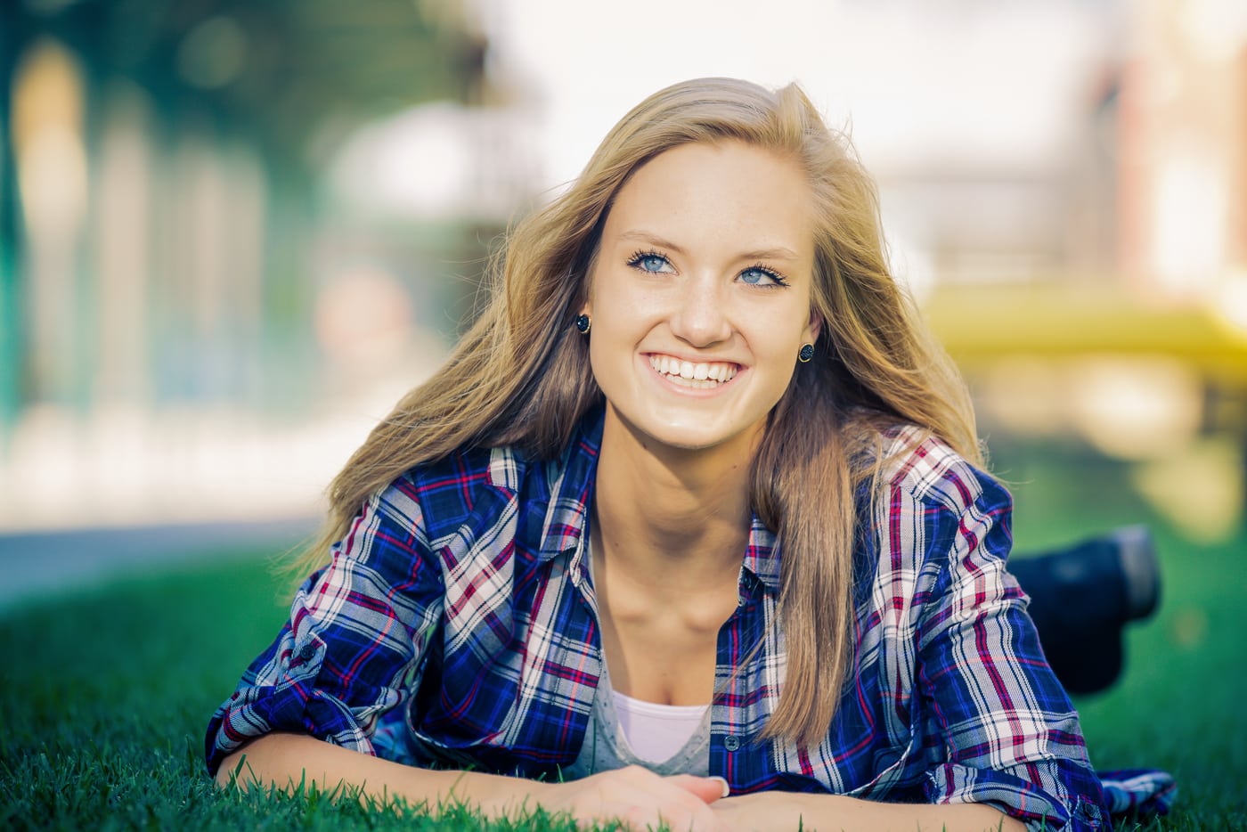 Senior plaid in grass, smiling.