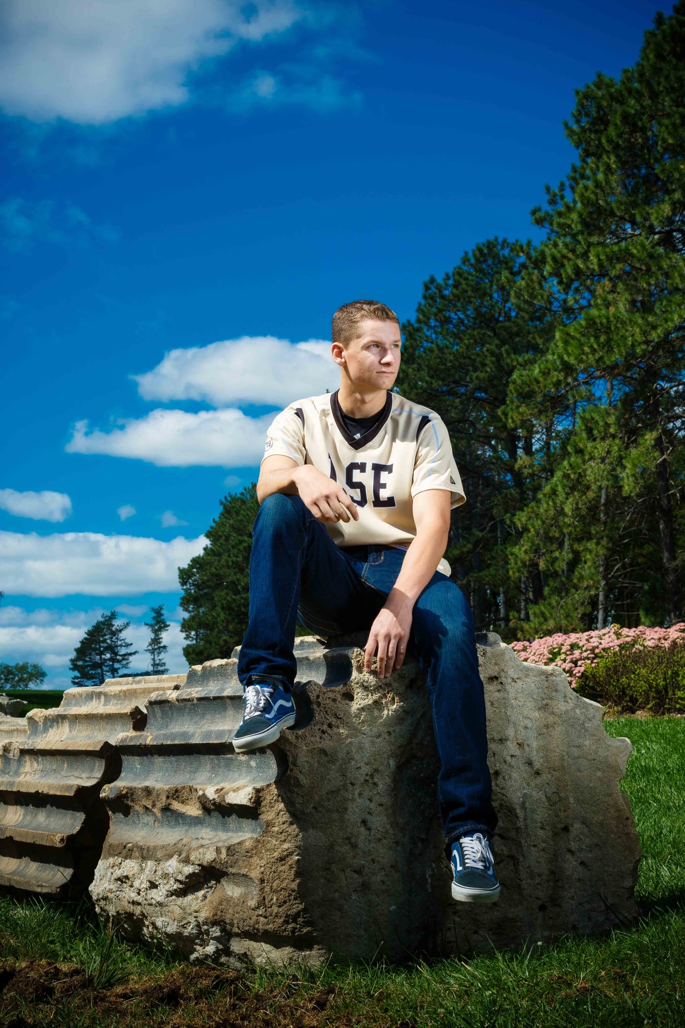 Senior boy on rock, blue sky.