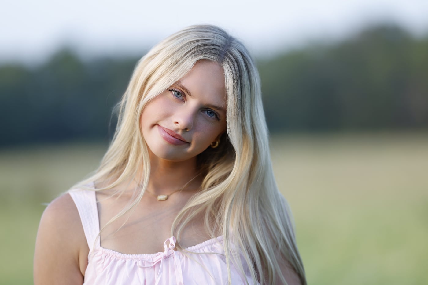 Blonde senior, pink top, field.