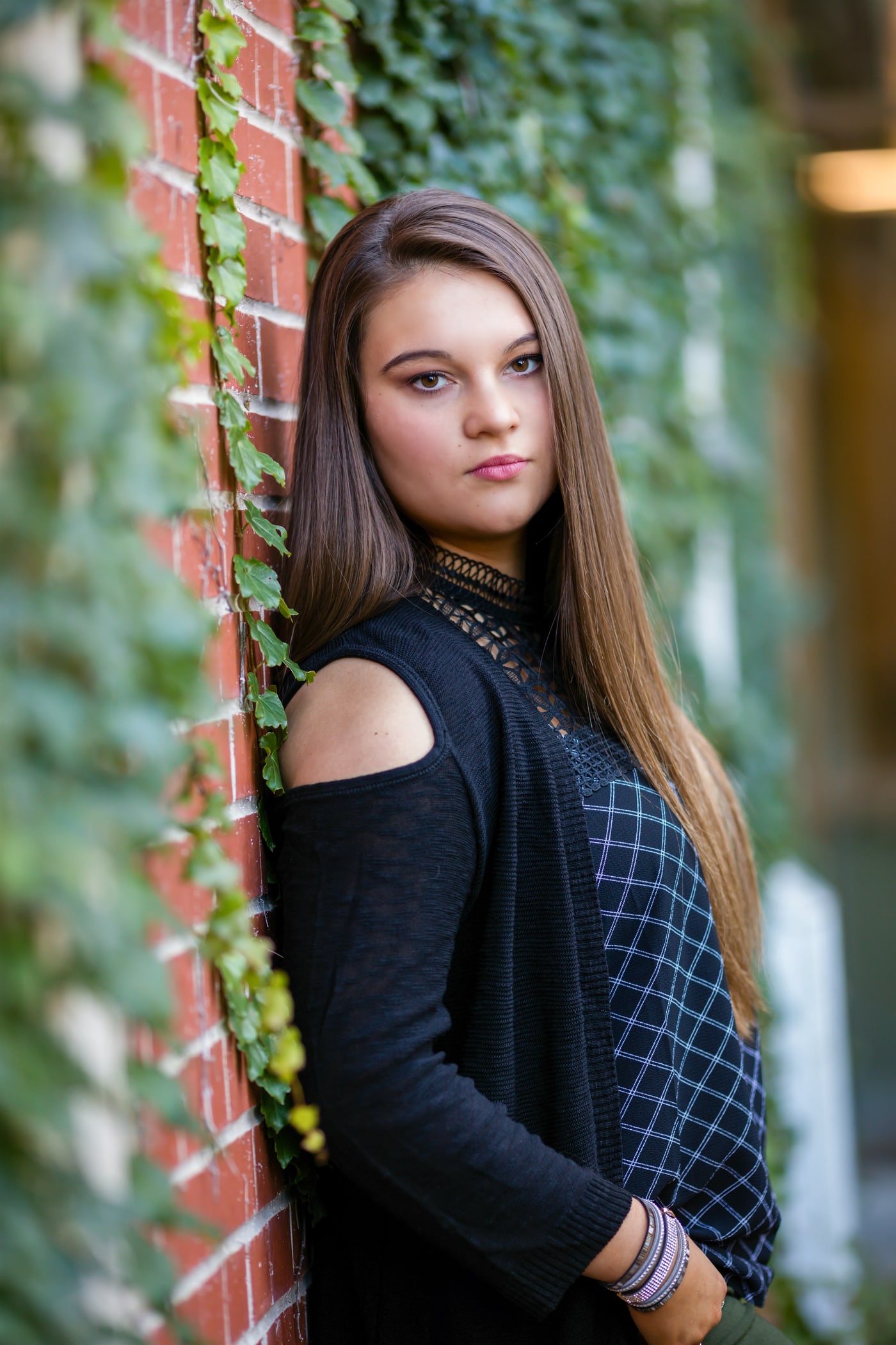 Urban brick senior portrait with confident direct gaze.