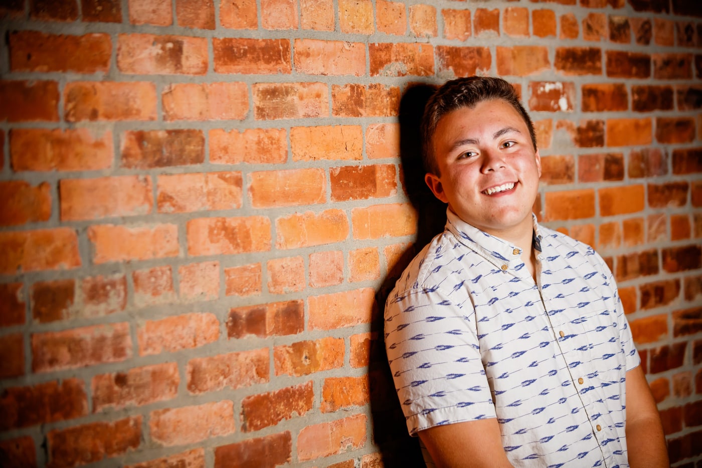 Senior portrait against warm brick wall.
