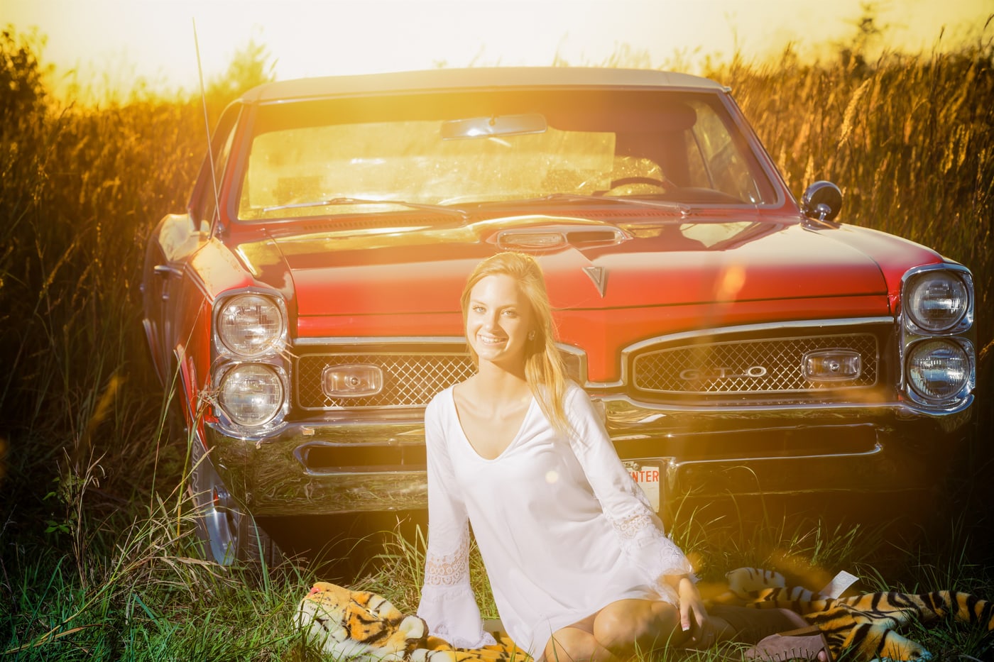 Classic-car senior portrait in warm field light.