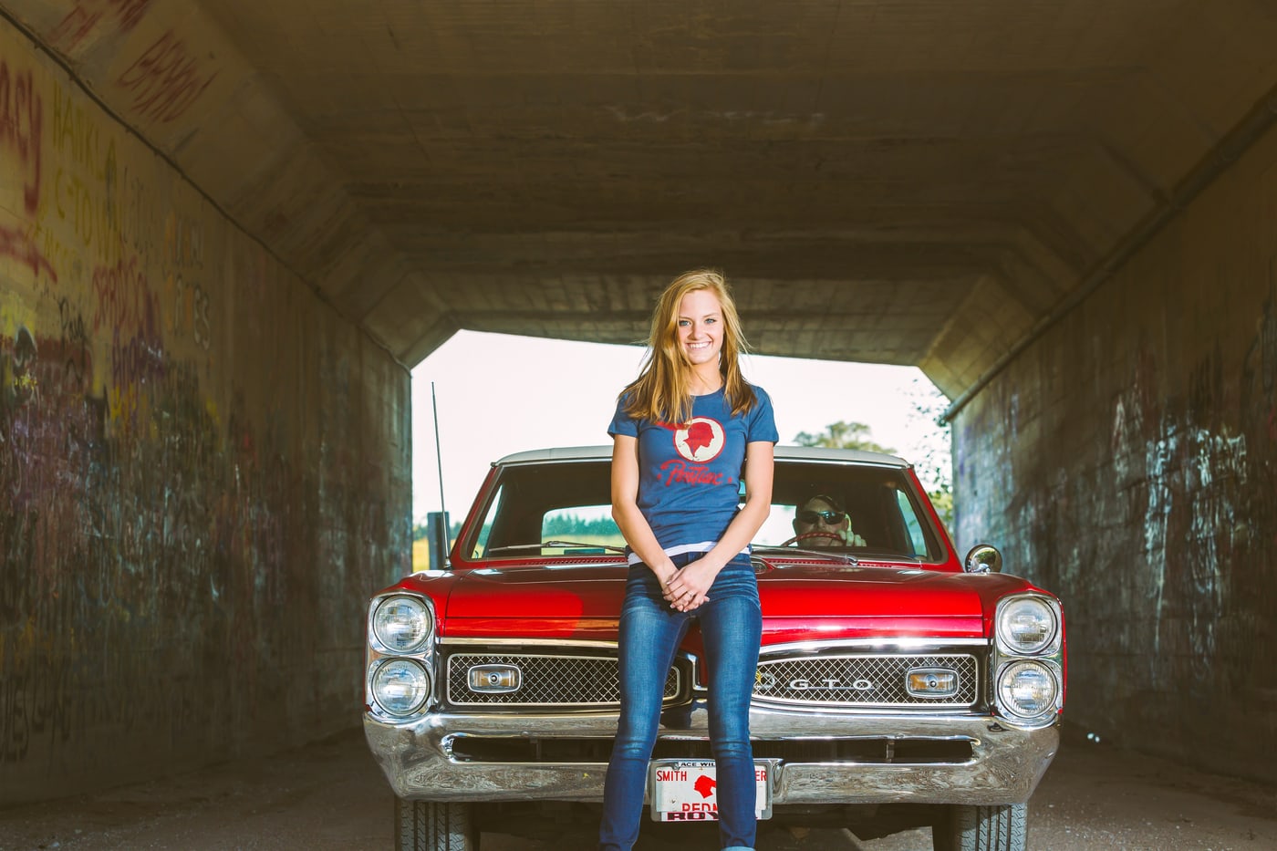 Classic-car senior portrait under bridge.