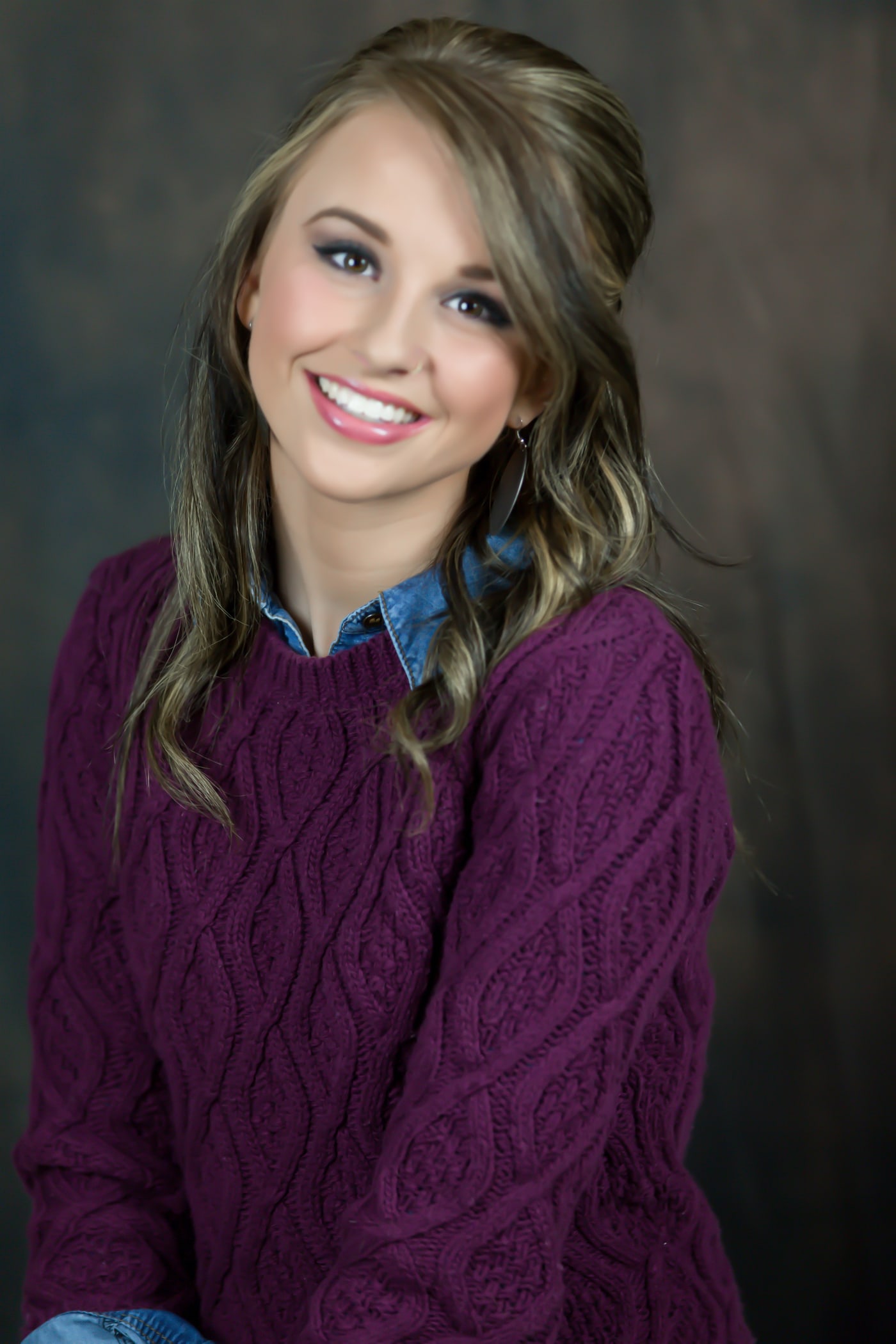 Studio senior portrait with polished smile.