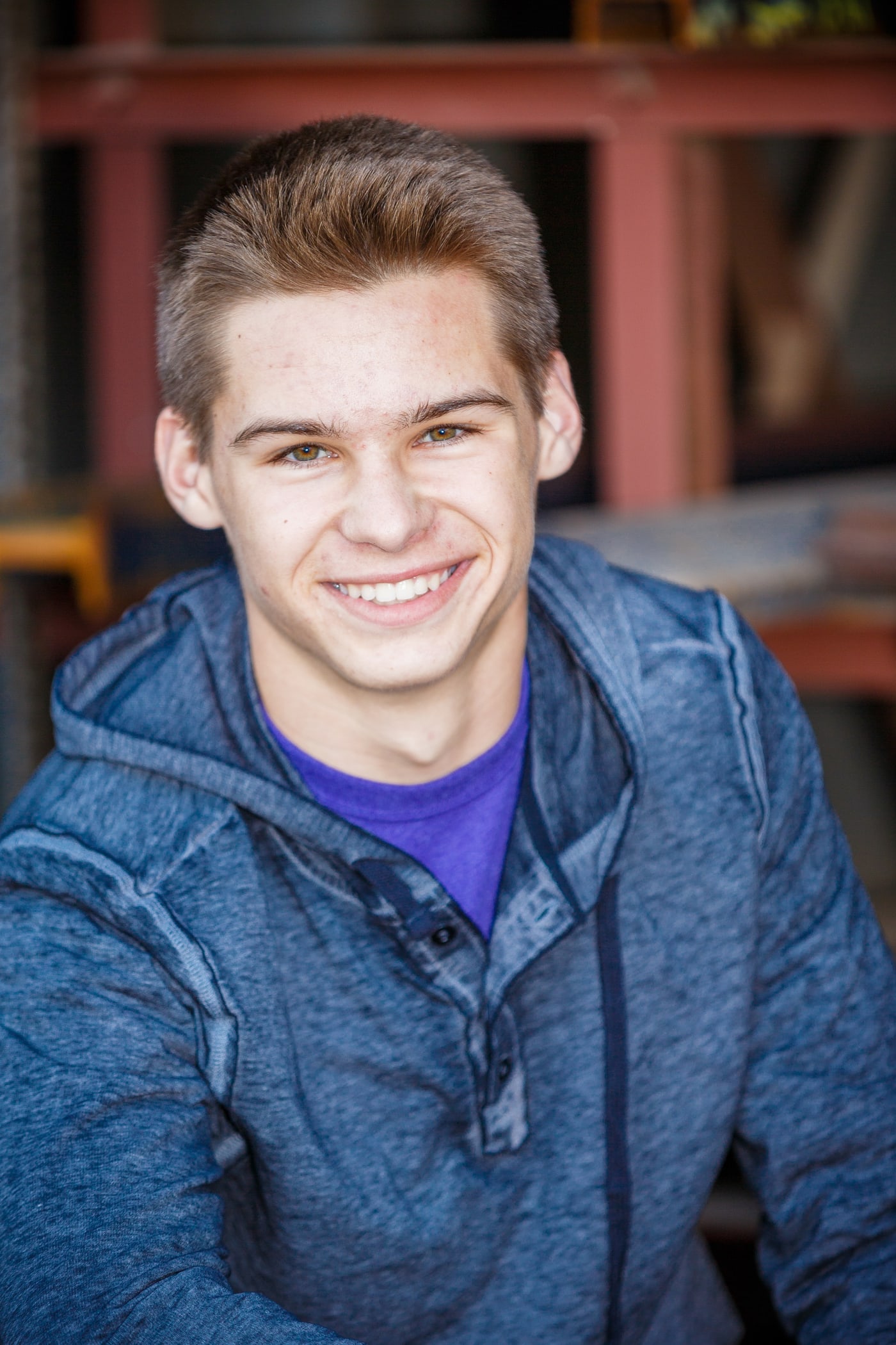 Senior portrait with blue jacket and brick background.
