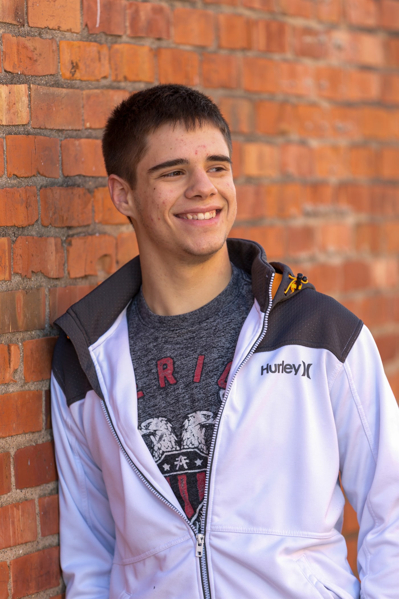 Senior portrait by brick wall in casual school style.