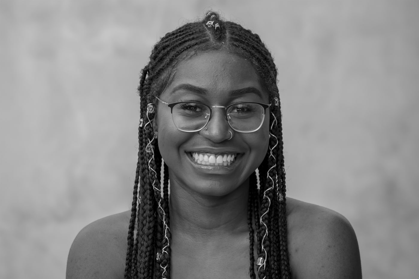 Black-and-white senior portrait with glasses and bright smile.