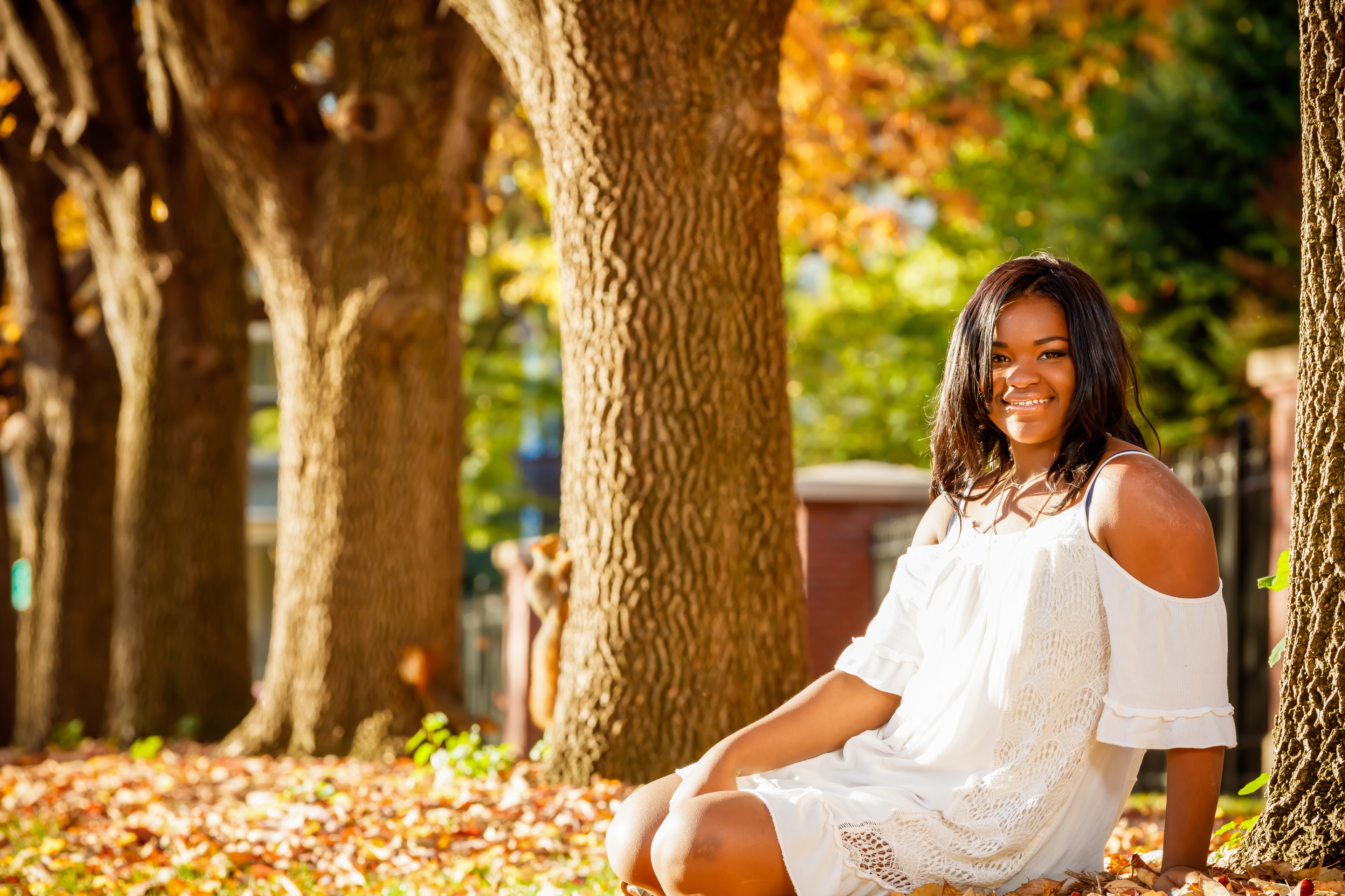 Bright outdoor senior portrait in white dress.