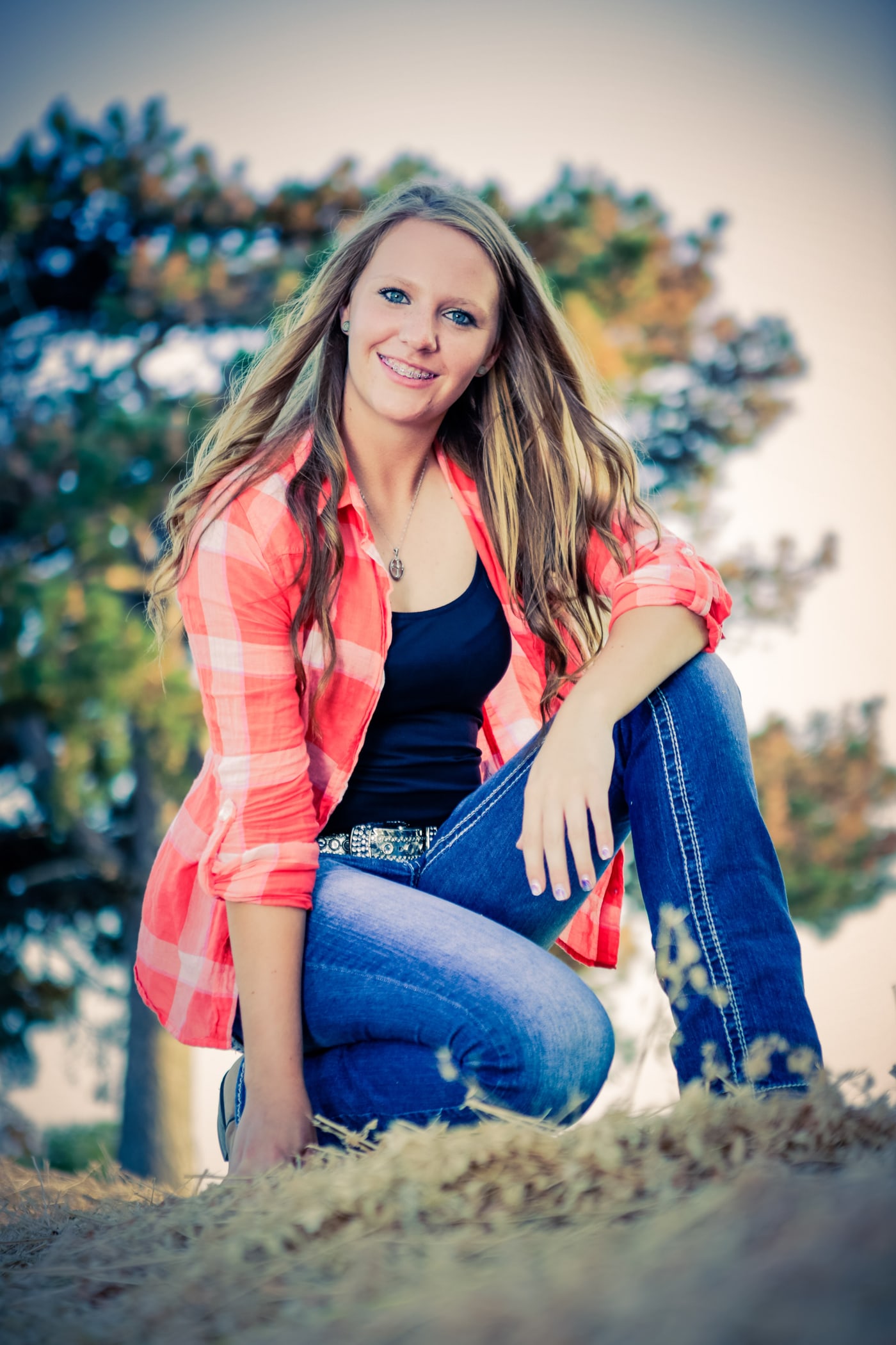 Outdoor senior portrait in plaid with open sky.