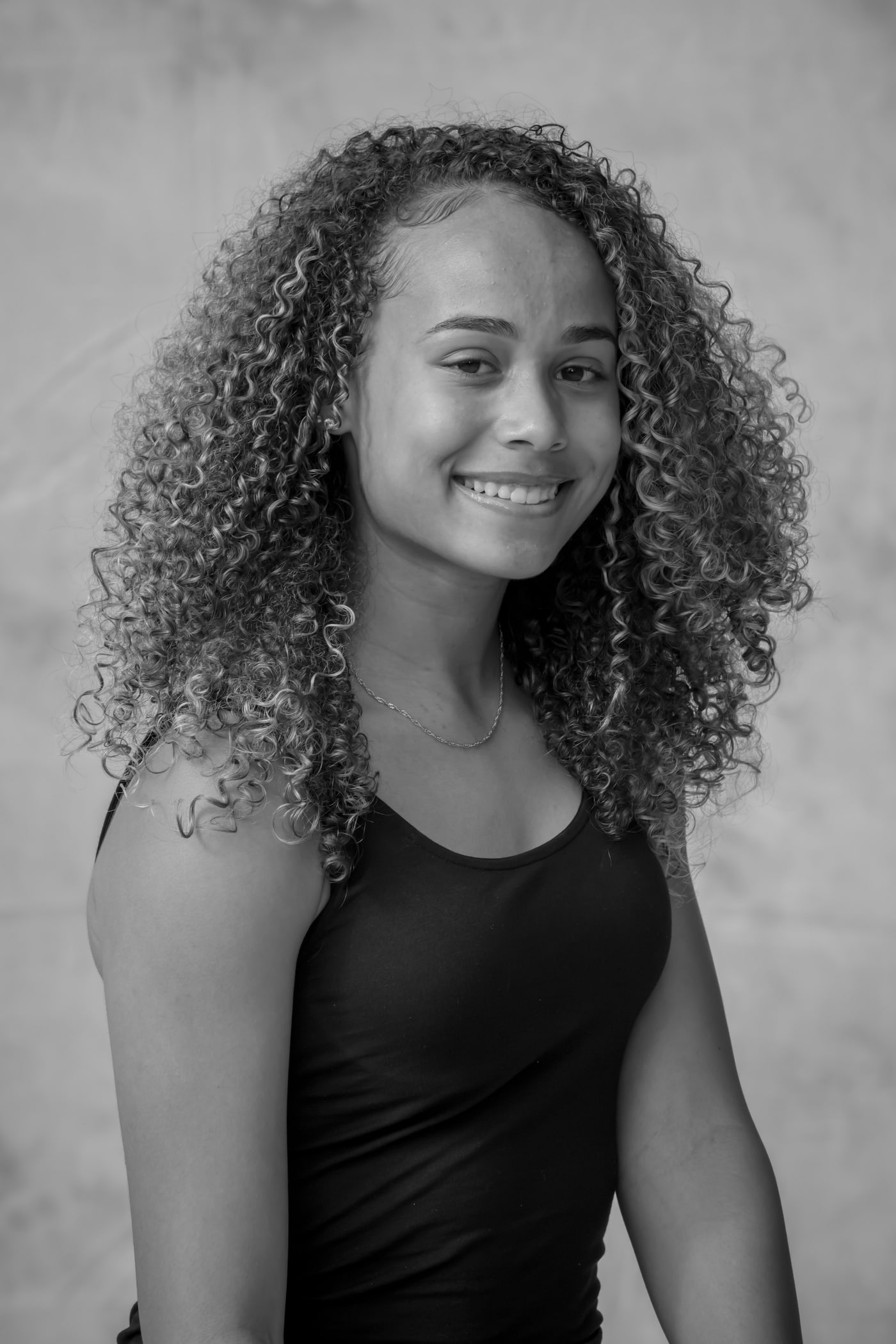 Black-and-white smiling senior portrait with curly hair.