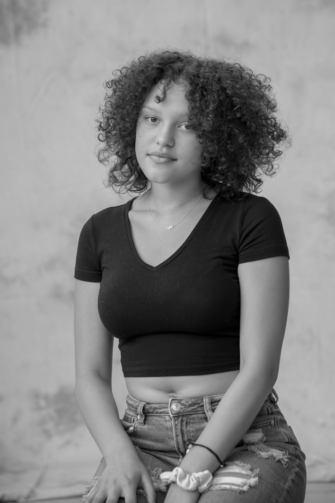 Black-and-white seated senior portrait with soft expression.