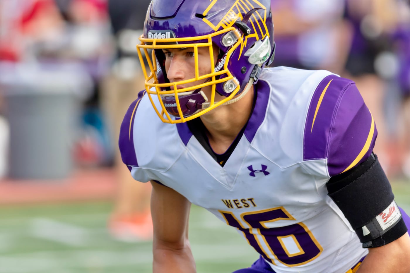 Football player West #16, purple helmet close-up.