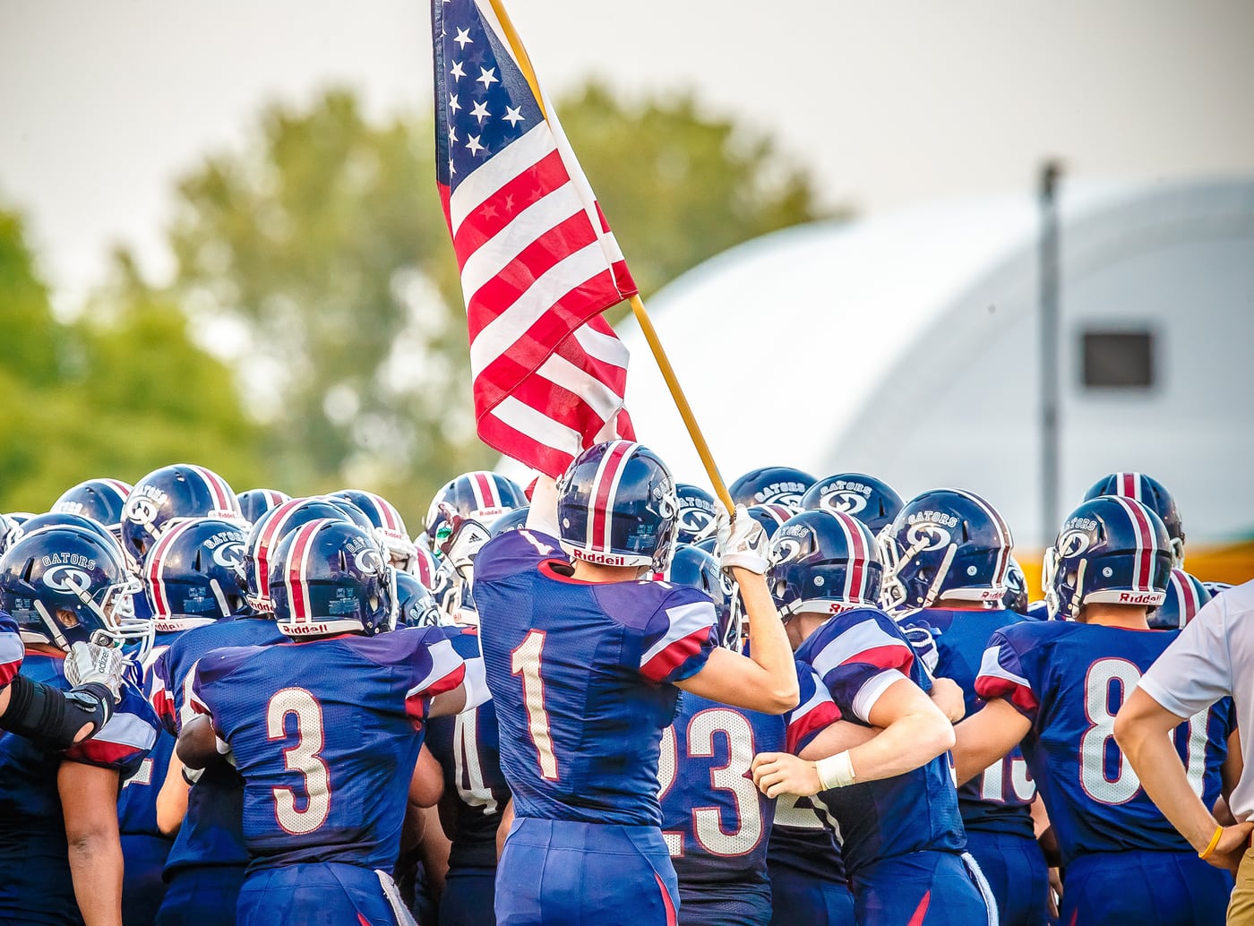 Team huddled behind American flag, Friday-night energy.