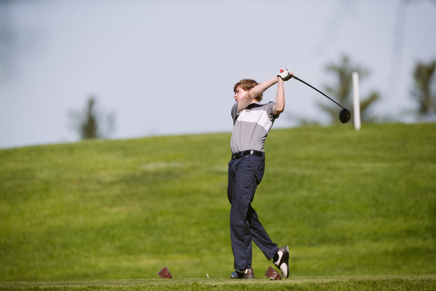 Golfer mid-swing on green, action.