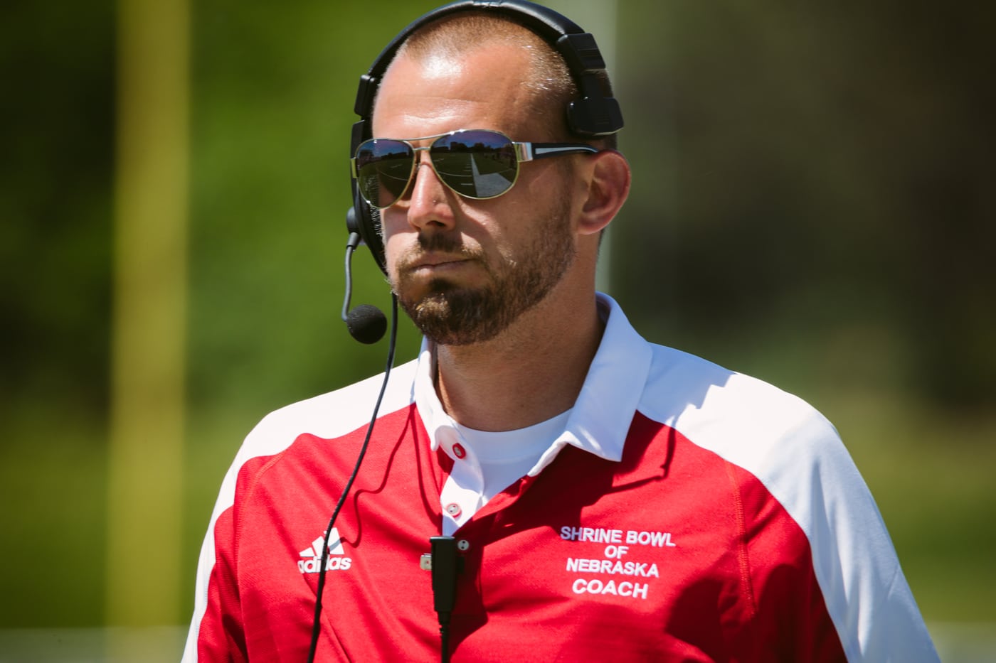 Shrine Bowl coach, headset + shades, documentary.