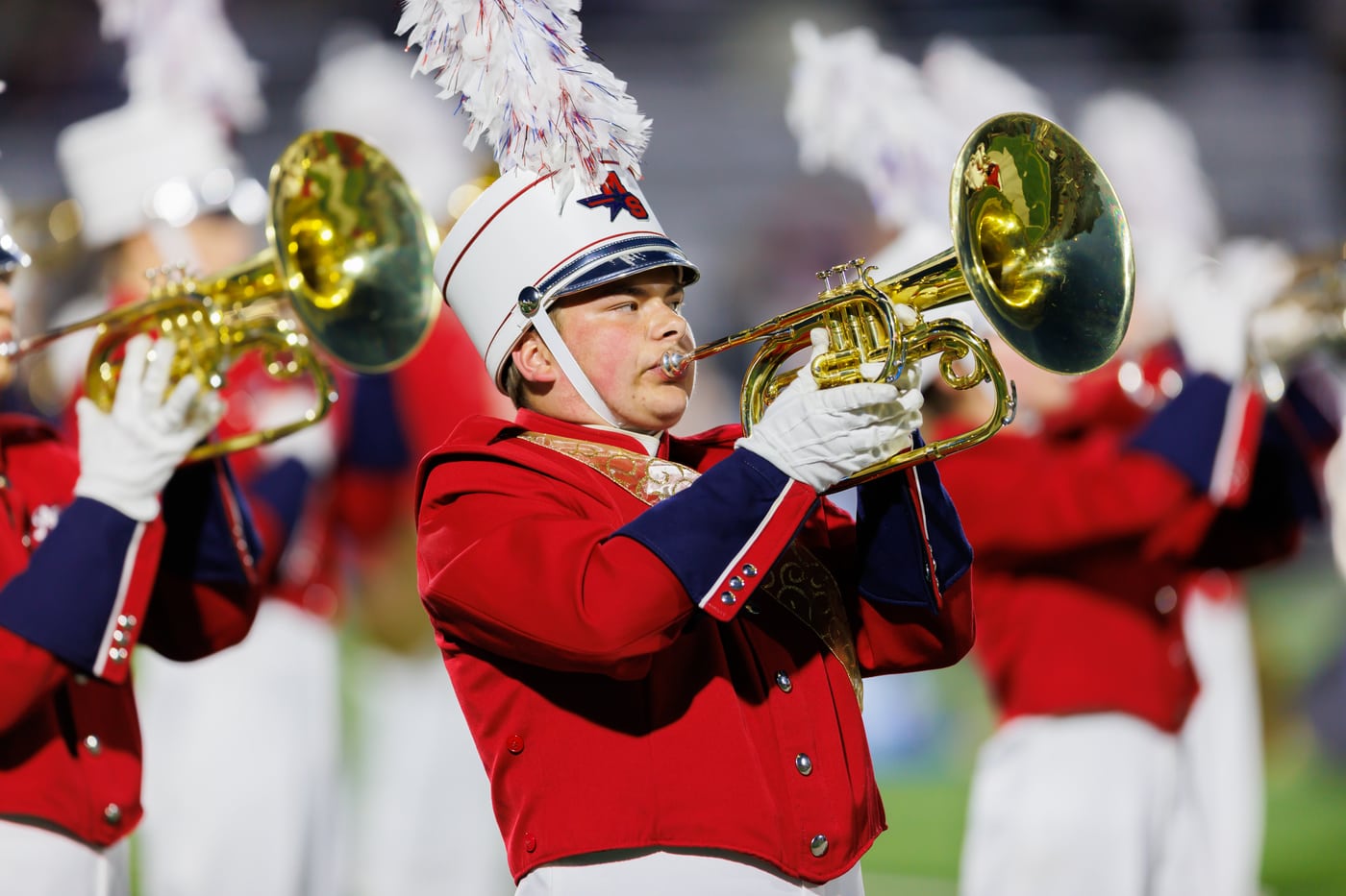 Marching band trumpets, red uniform, band/motion.